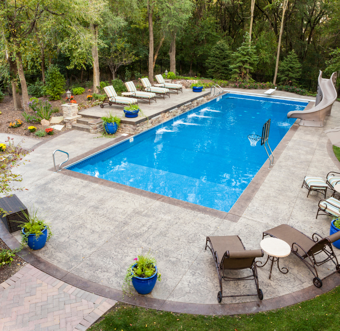 A large swimming pool surrounded by chairs and plants