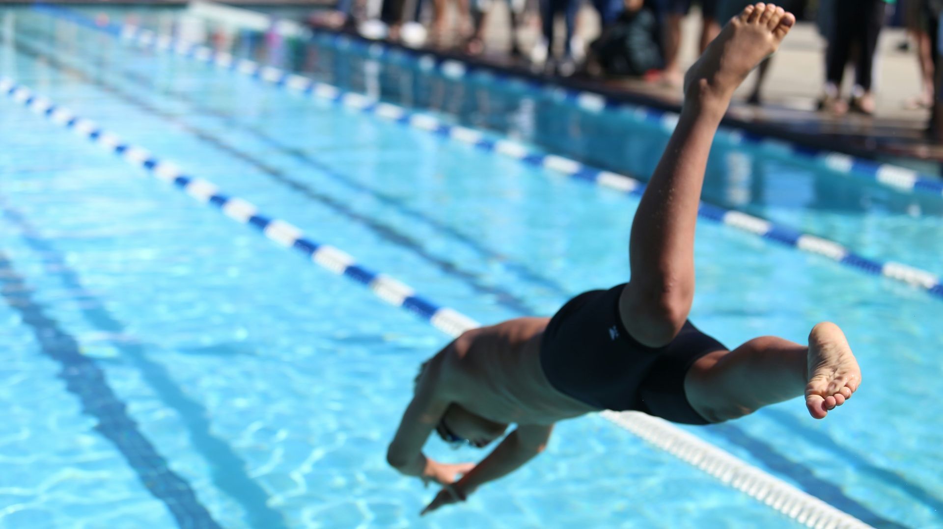 A man is doing a handstand in a swimming pool.