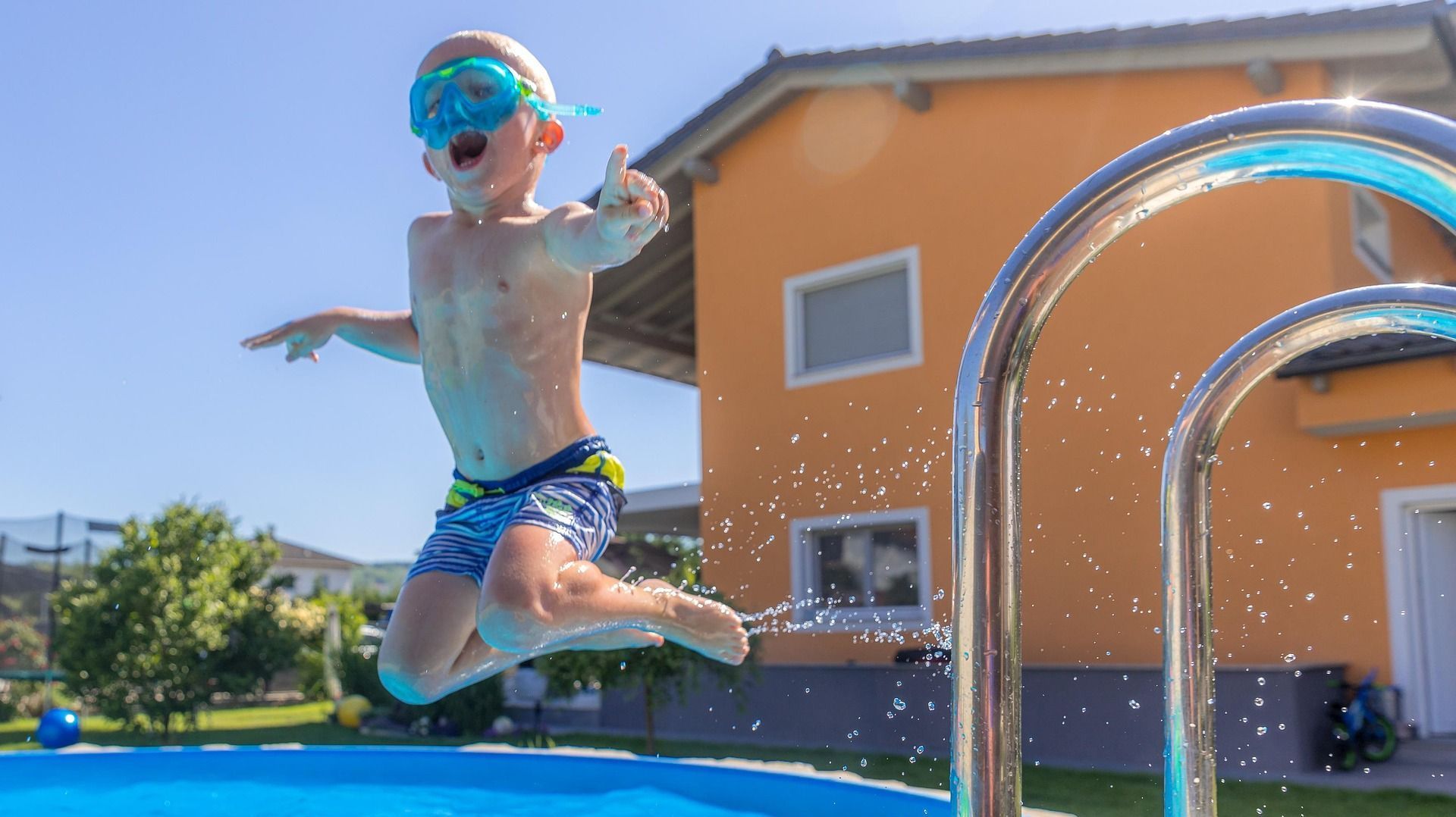 A young boy is jumping into a swimming pool.