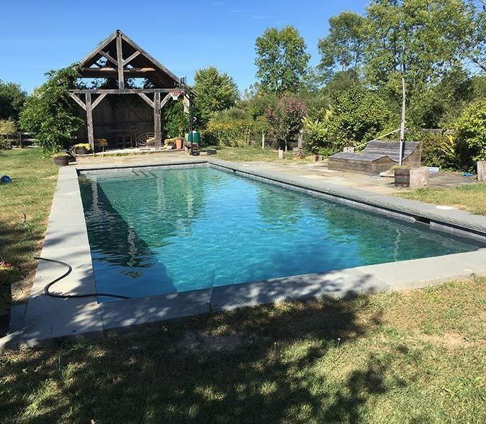 A large swimming pool with a gazebo in the background