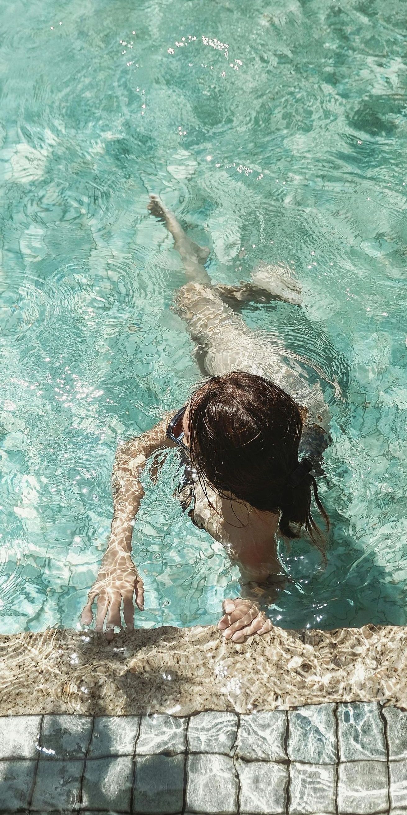 A woman is swimming in a swimming pool.