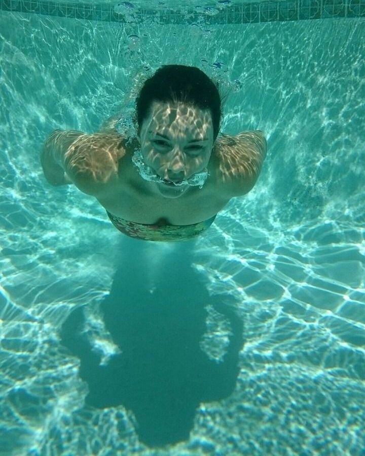 A woman is swimming underwater in a swimming pool.