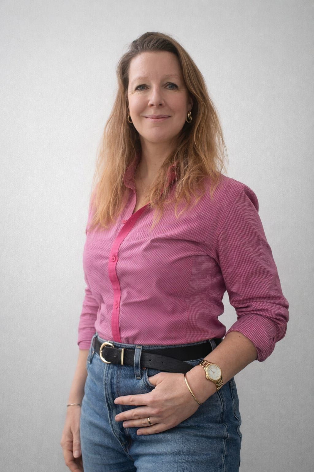 Twee vrouwen in een vergadering, een van hen glimlachend, aan een houten tafel met papieren voor zich in een lichte ruimte.