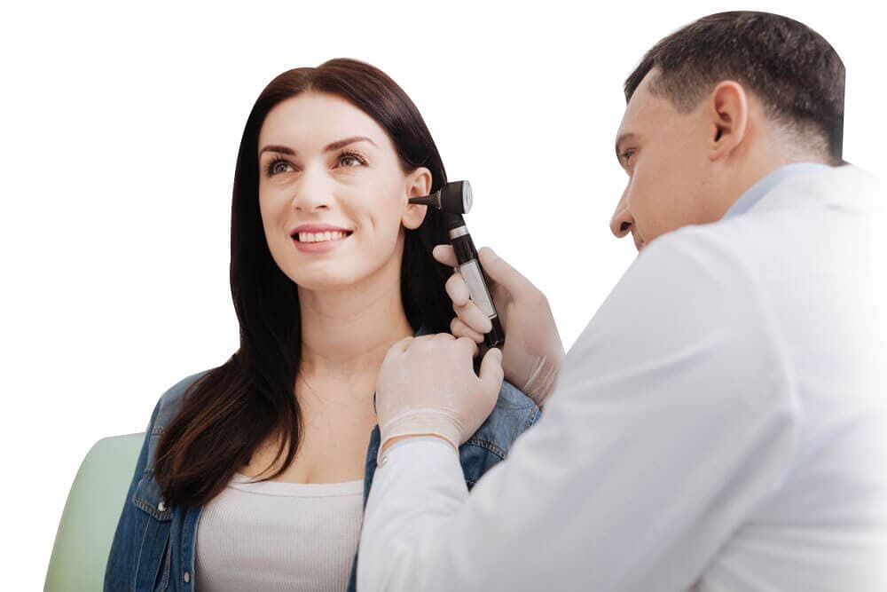 Un médico está examinando la oreja de una mujer con un otoscopio.