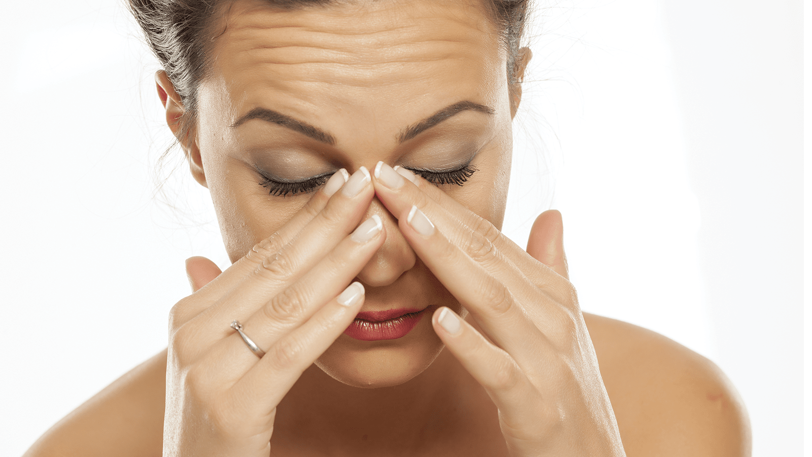 Una mujer se tapa la nariz porque le duele la cabeza.