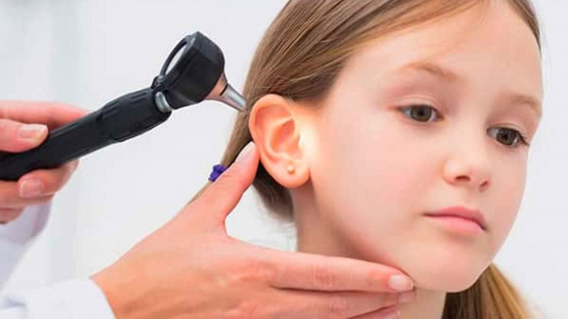 A una niña le examina el oído un médico.