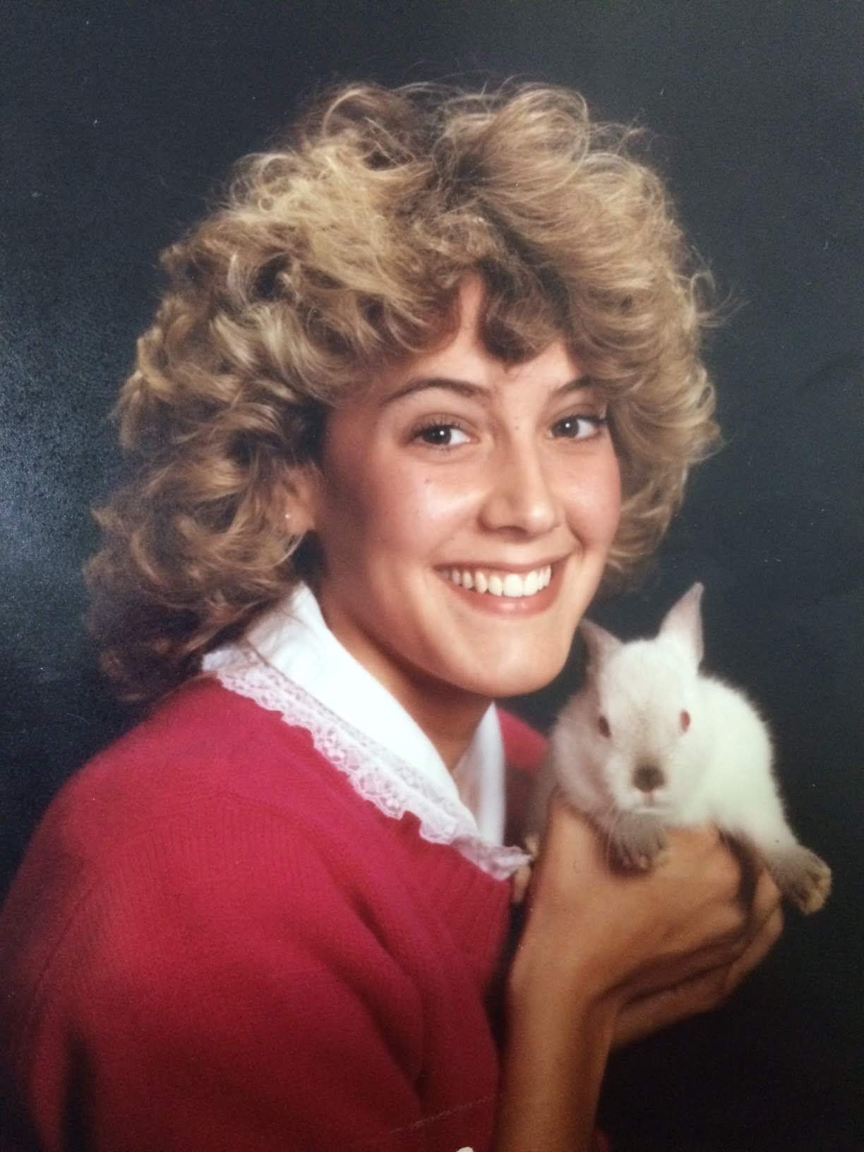 A picture of Sue a woman with curly blonde hair and brown eyes holding a rabbit