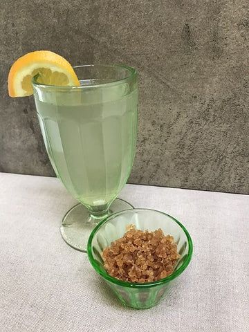 dry water kefir grains in a bowl next to a glass of fermented water kefir