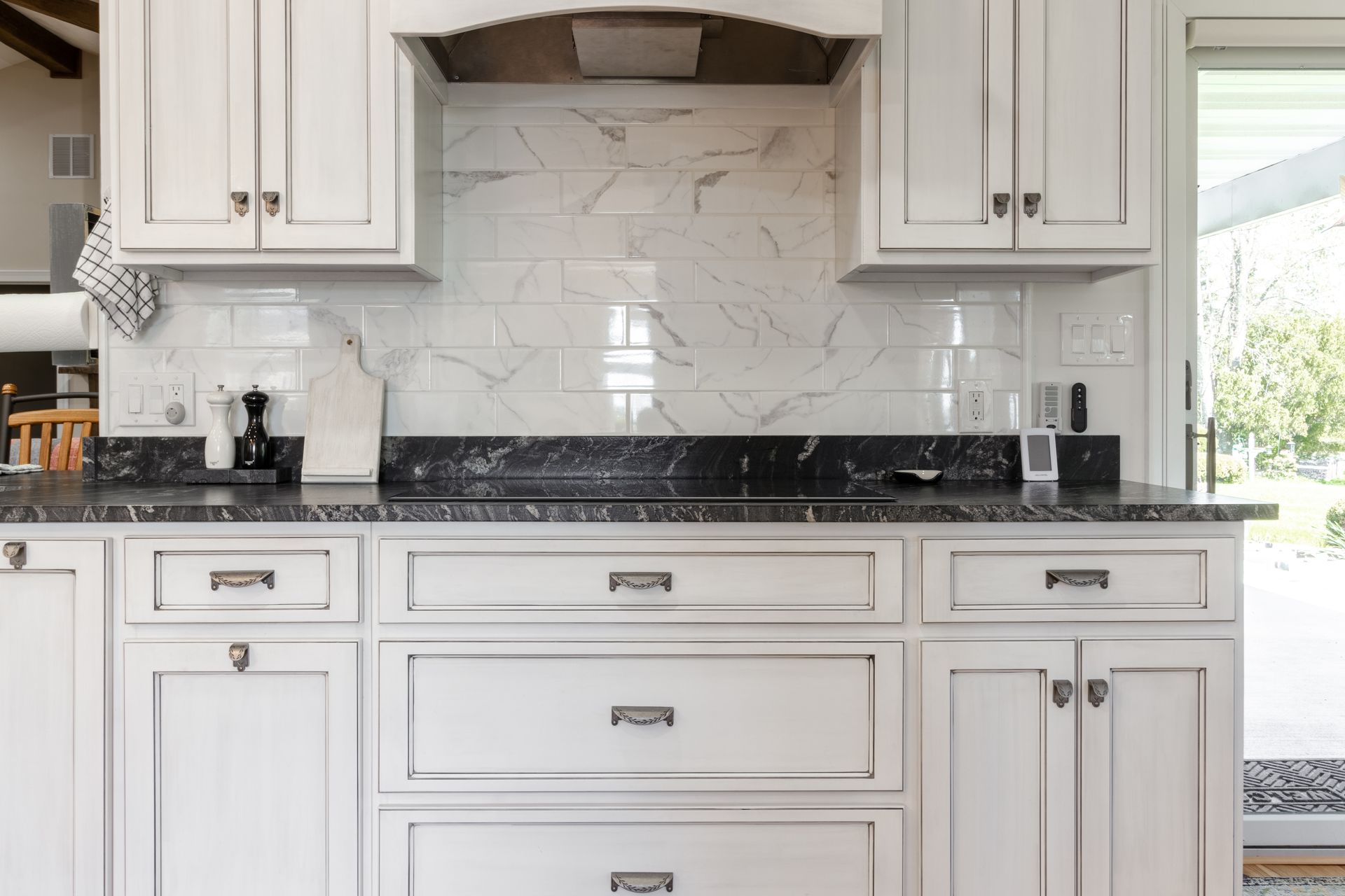 White kitchen cabinets with black countertops and marble tile backsplash.