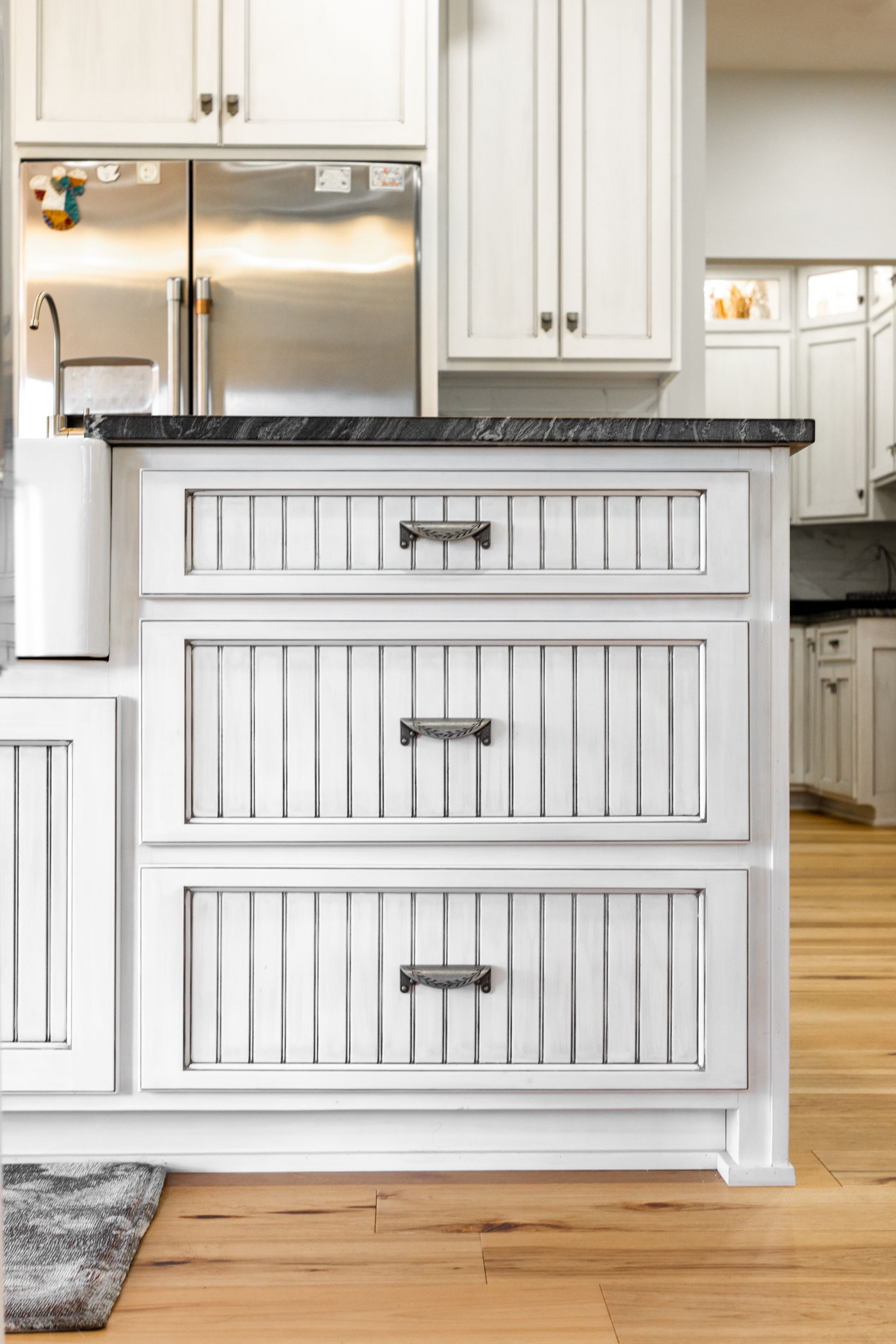 White kitchen island with three drawers, dark countertop, and decorative vertical slats.