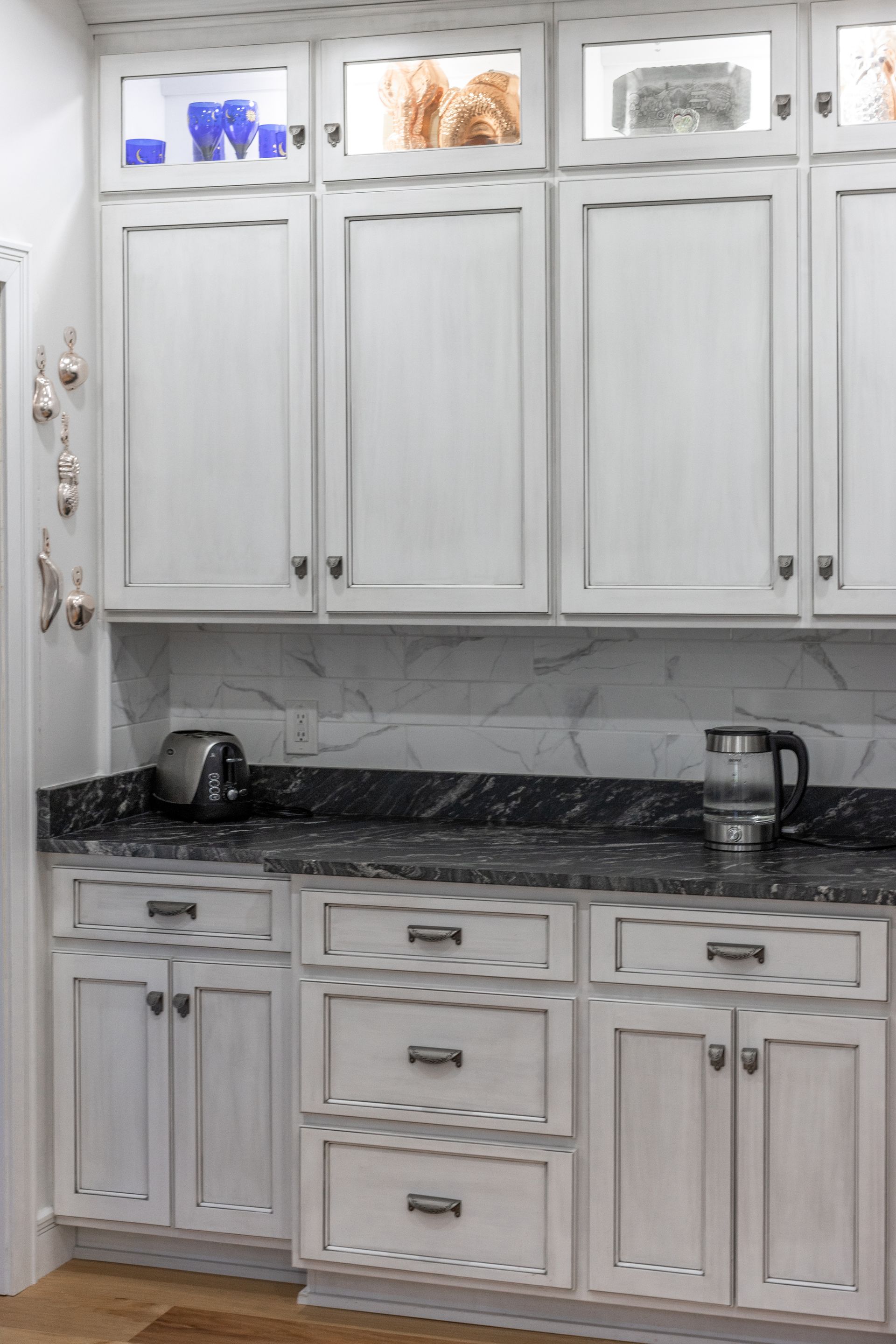 White kitchen cabinets with black countertops and appliances.