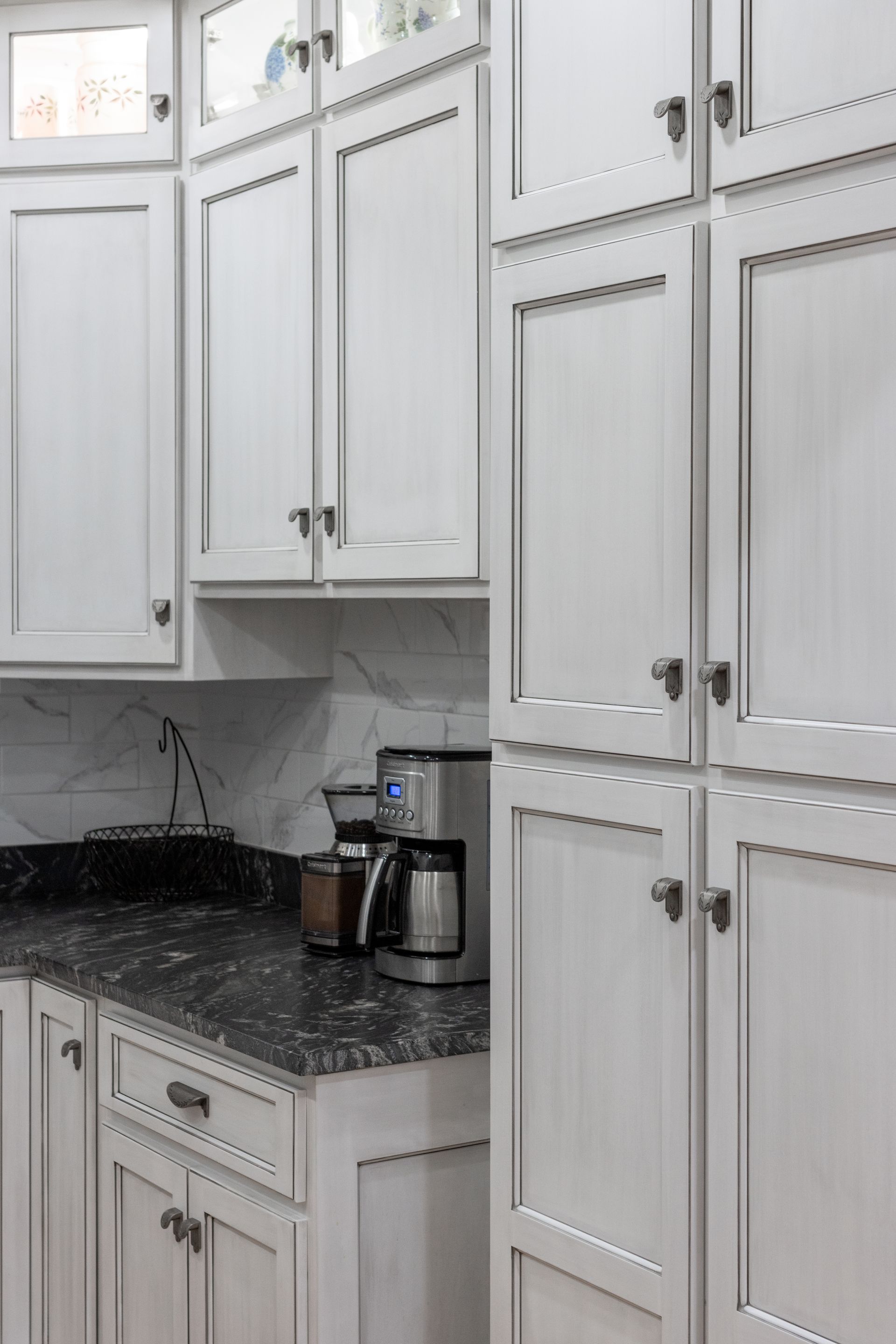 White kitchen cabinets with black countertop, coffee maker.
