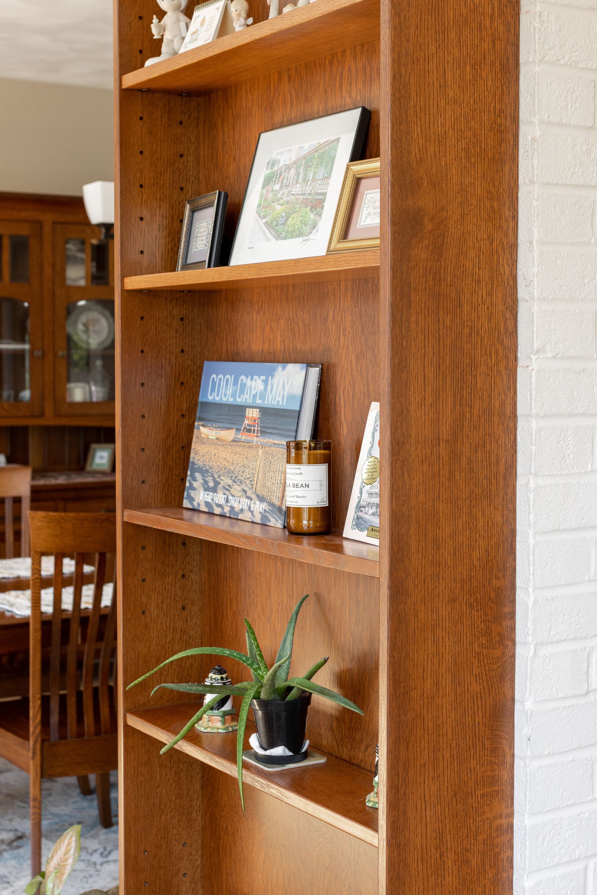 Wooden bookshelf filled with decorative items against a white brick wall.