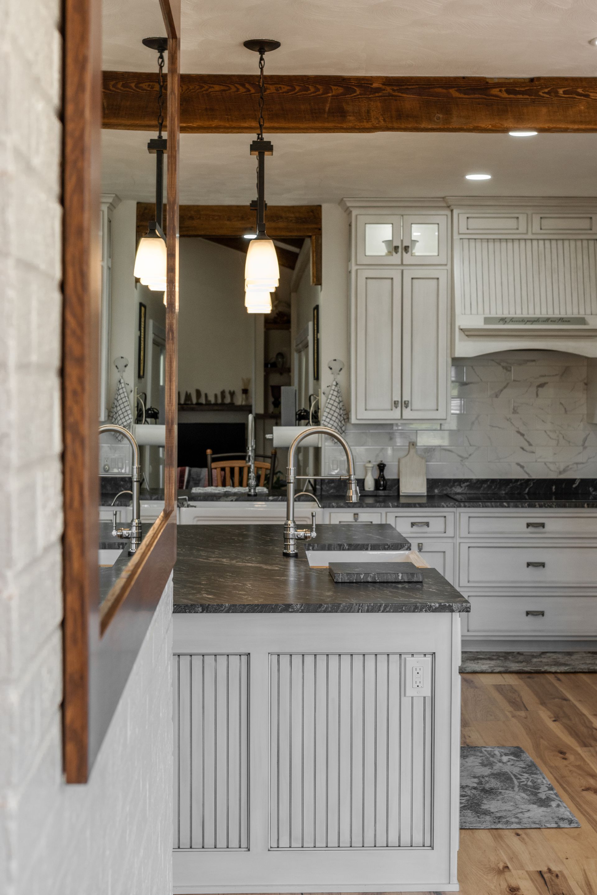 Kitchen with gray cabinets, island, and wood accents; a mirror reflects the space.