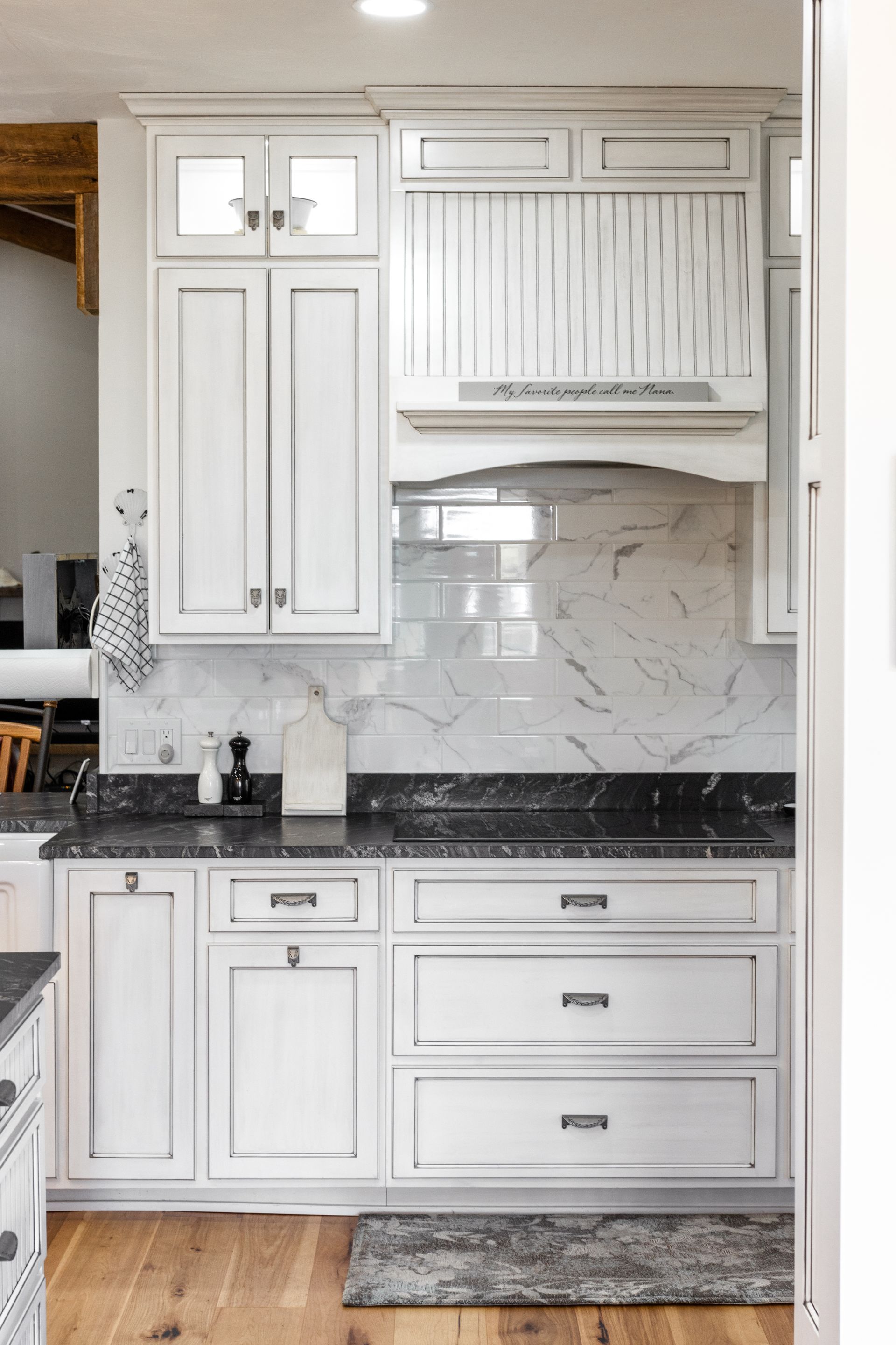 White kitchen cabinets with black countertops and marble backsplash.
