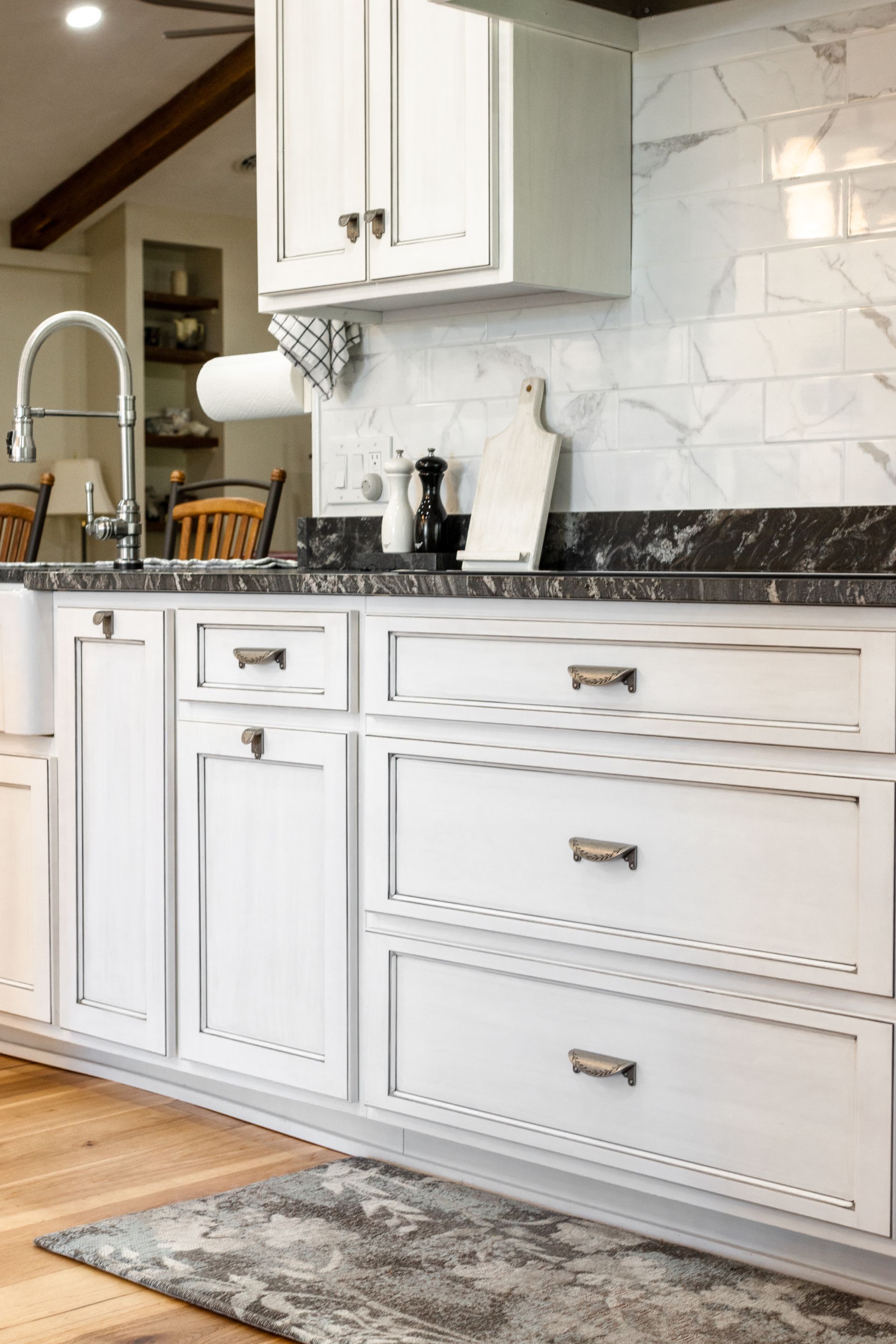 White kitchen cabinets with black countertops and marble tile backsplash.