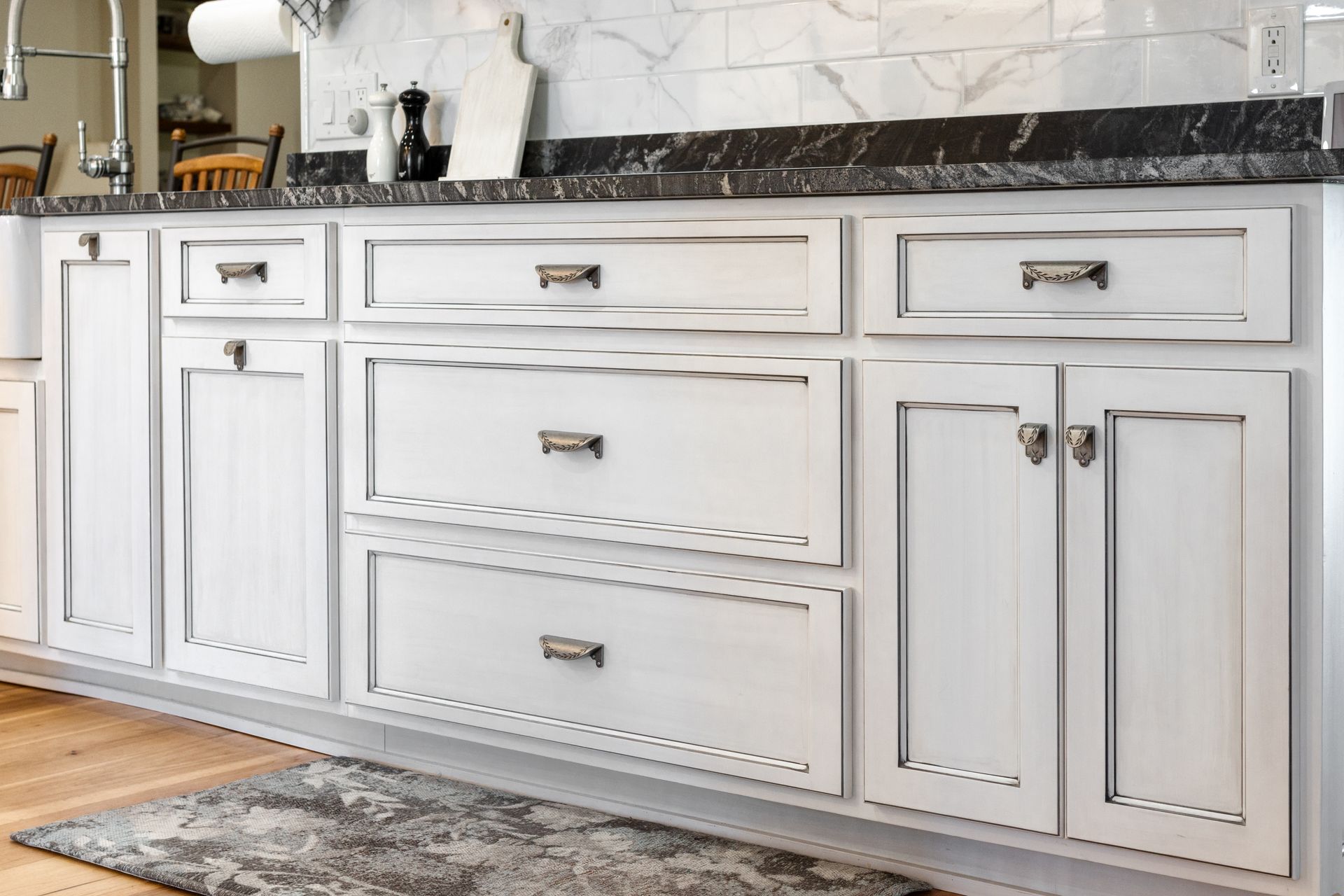 White kitchen cabinets with black countertop and silver hardware.