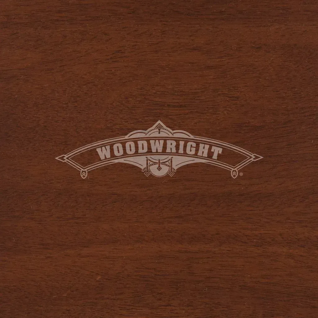 Woodwright logo on a dark brown wooden surface. The logo is light grey.