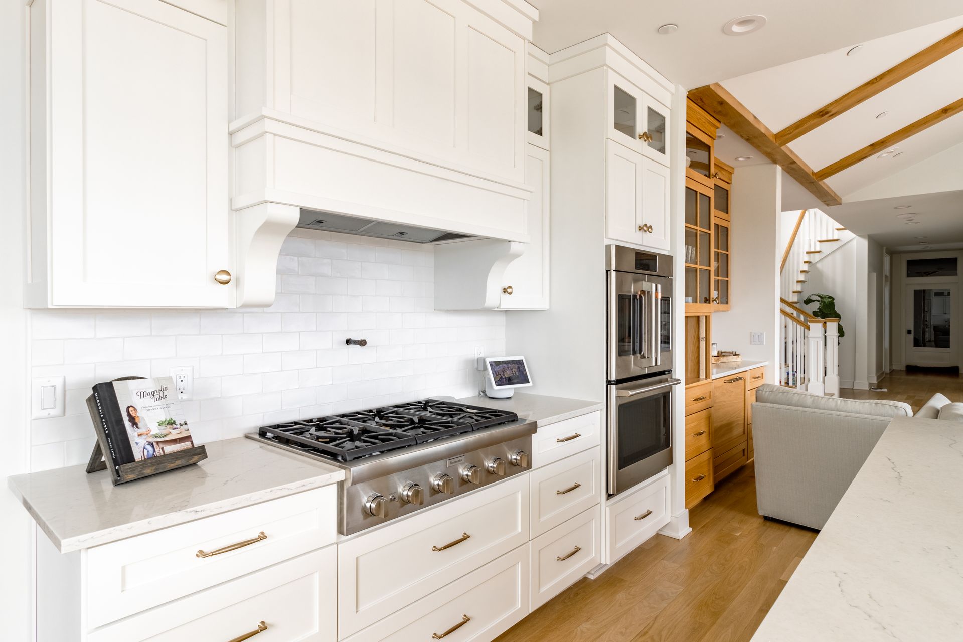 White kitchen with gas range, stainless appliances, and wooden accents.