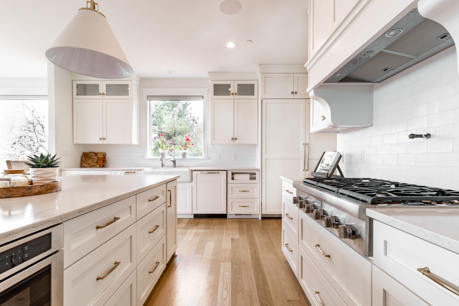 White kitchen with island, cabinets, appliances, and wood floor.