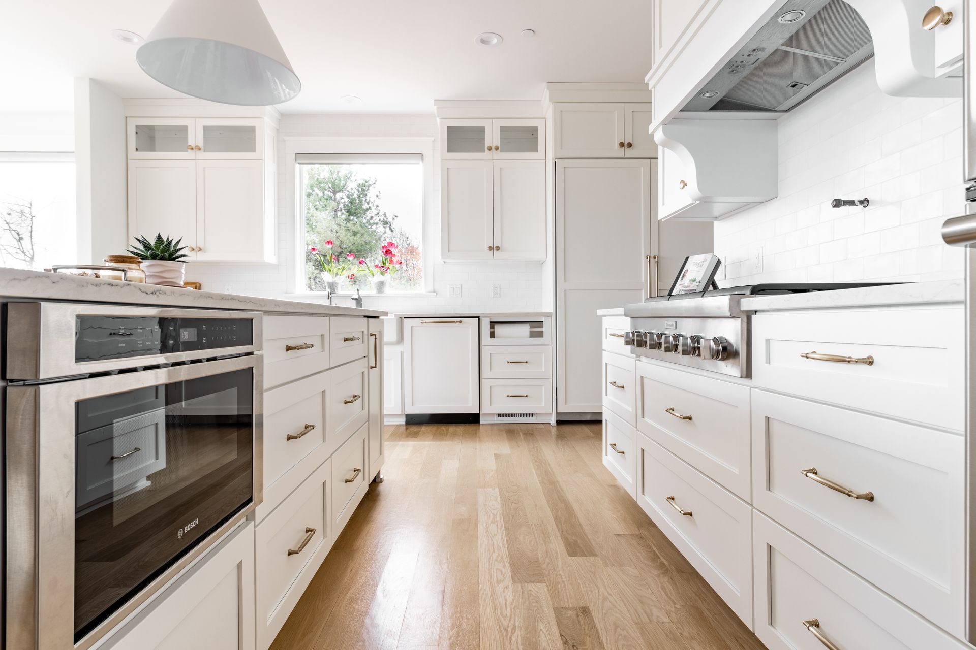 Bright white kitchen with hardwood floors, cabinets, and appliances.