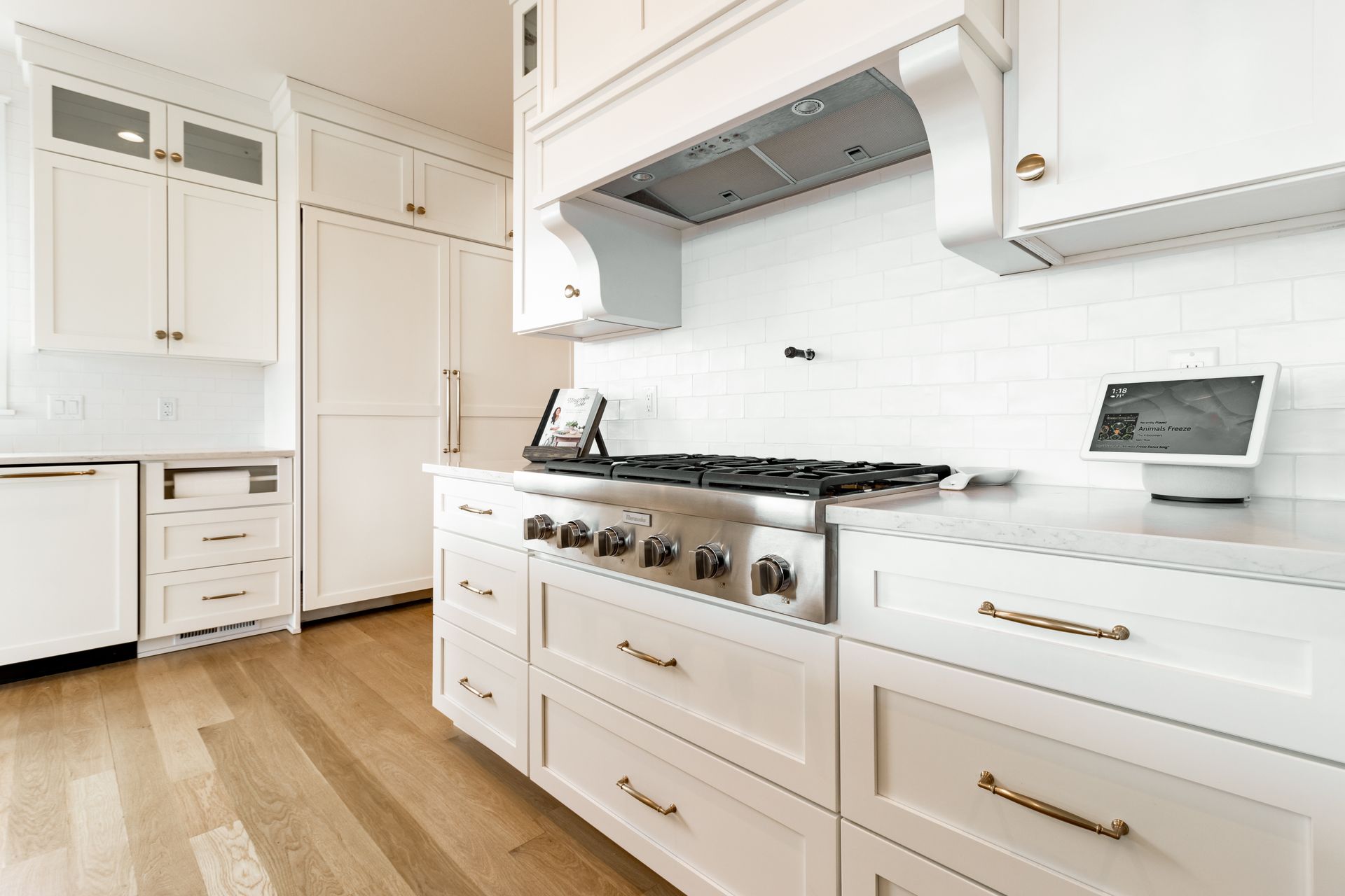 White kitchen with stainless steel appliances, white cabinets, and wooden floors.