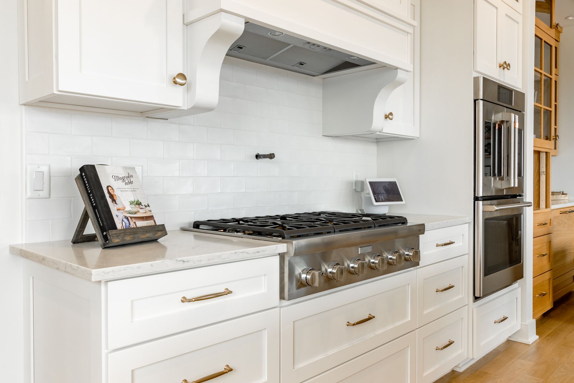 White kitchen with gas range, range hood, and double oven.