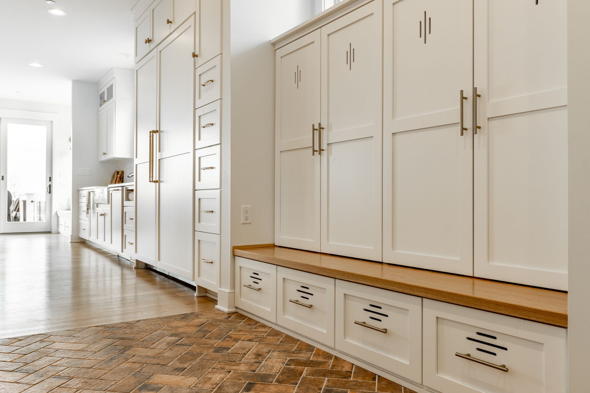 White built-in storage cabinets with drawers and bench, hardwood floor.
