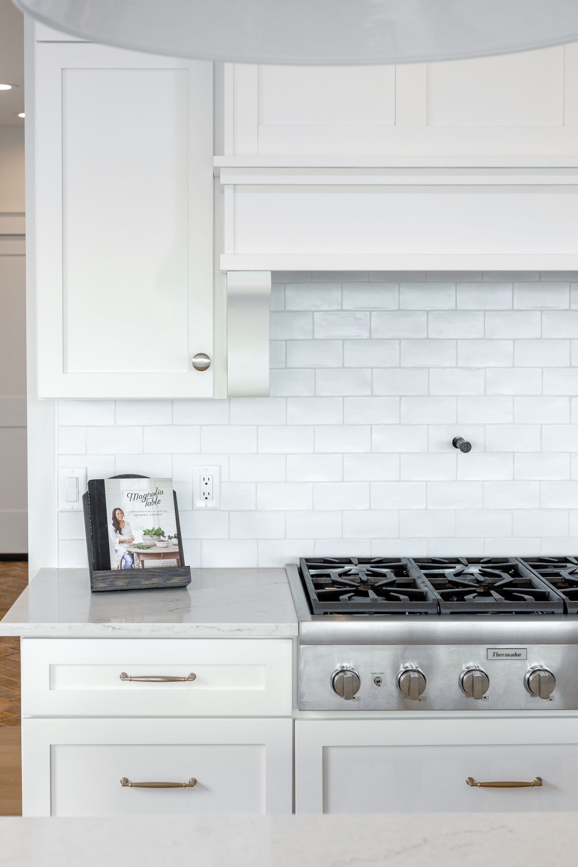 White kitchen with stove, cabinets, and cookbook on countertop.