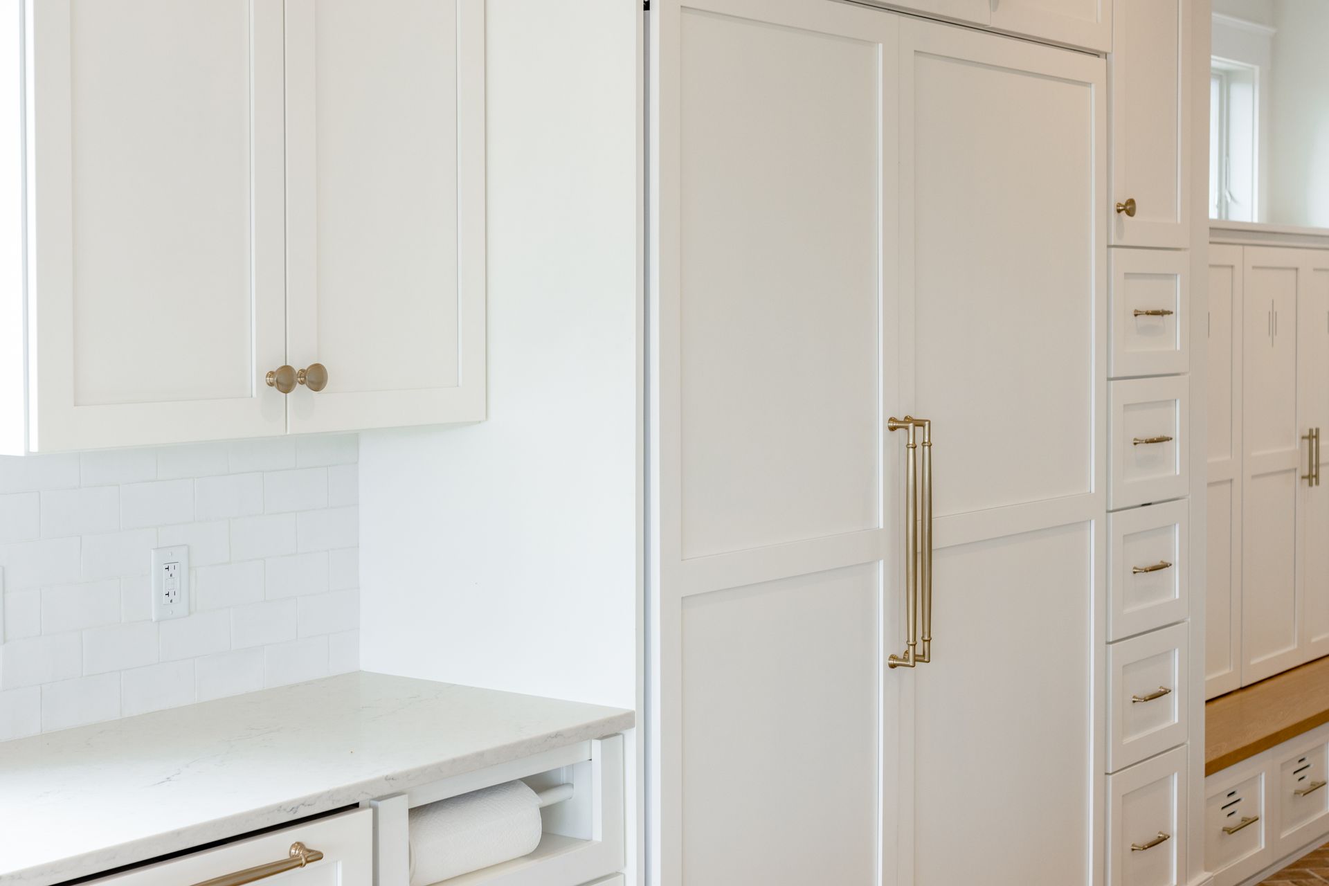White kitchen cabinets and refrigerator with gold hardware.