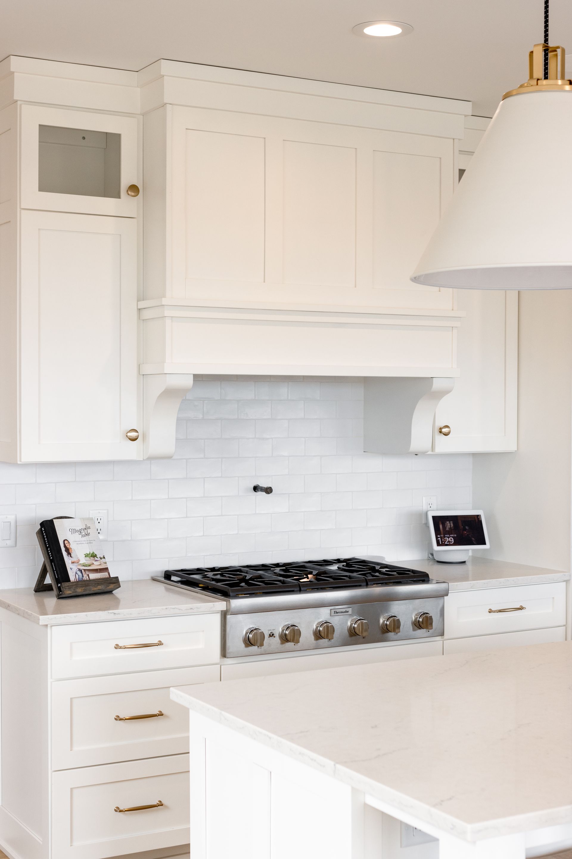White kitchen with stove, range hood, cabinets, and a kitchen island.