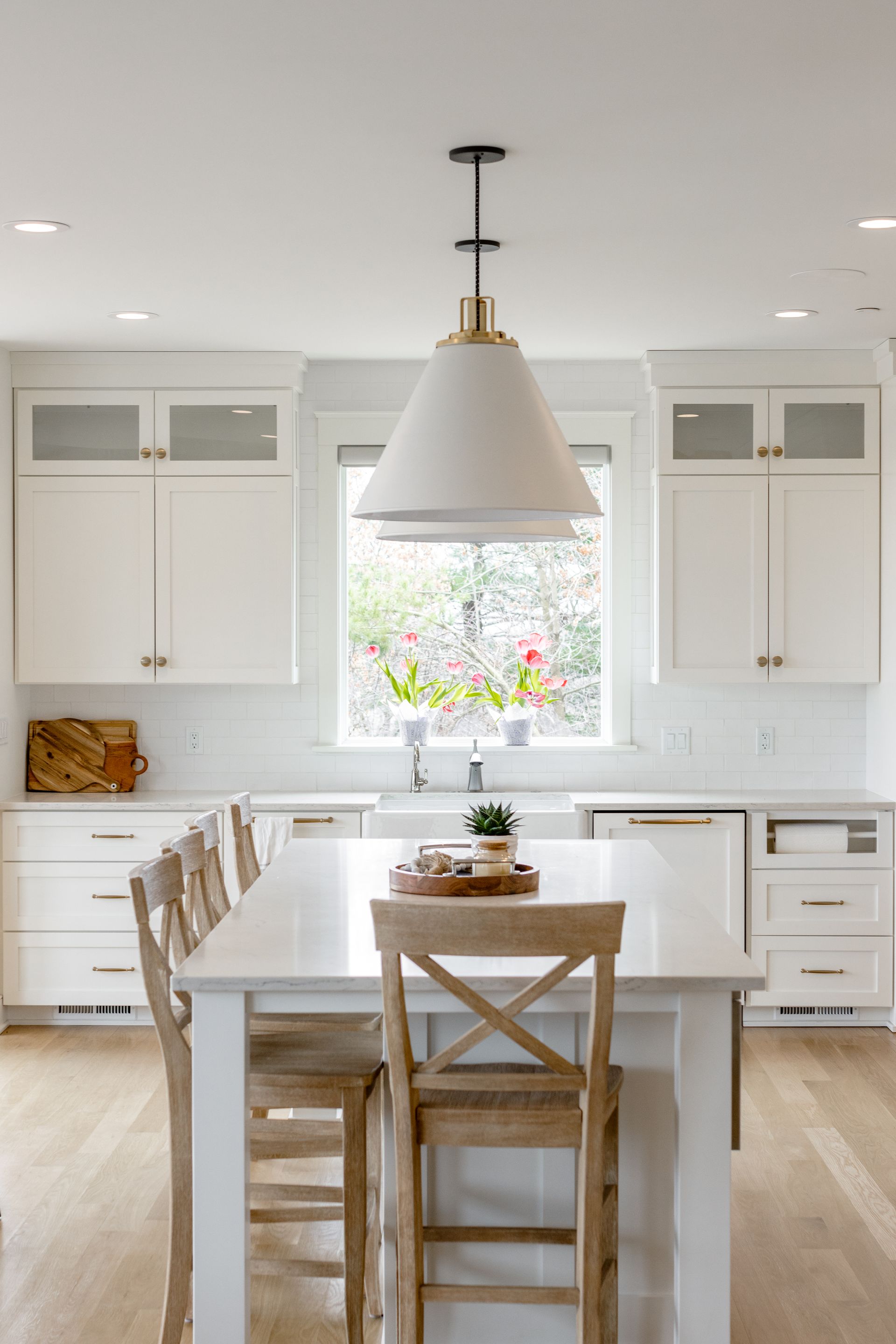 White kitchen with island, pendant light, and wooden bar stools.