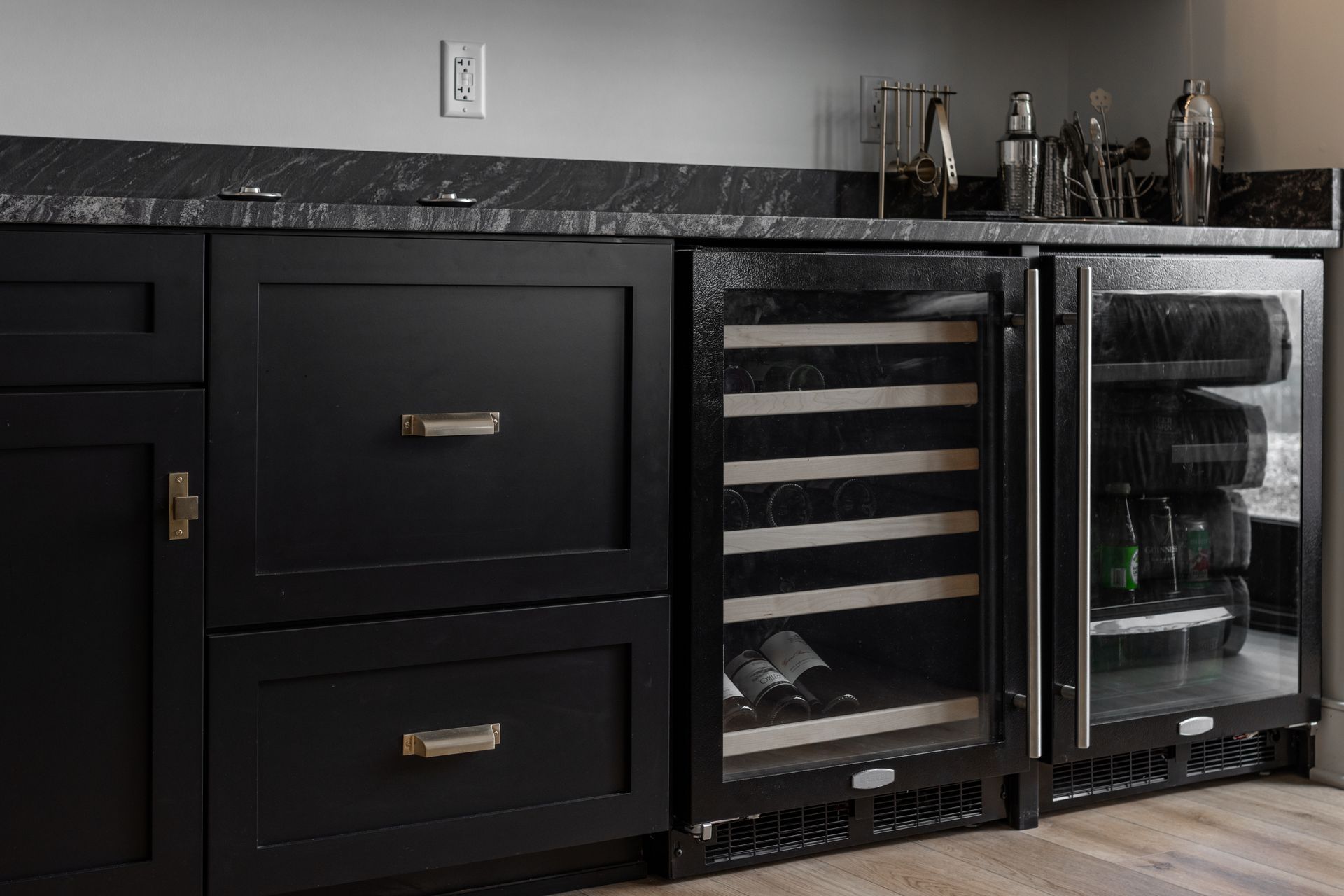 Black cabinets with a wine cooler, a beverage fridge, and a granite countertop.