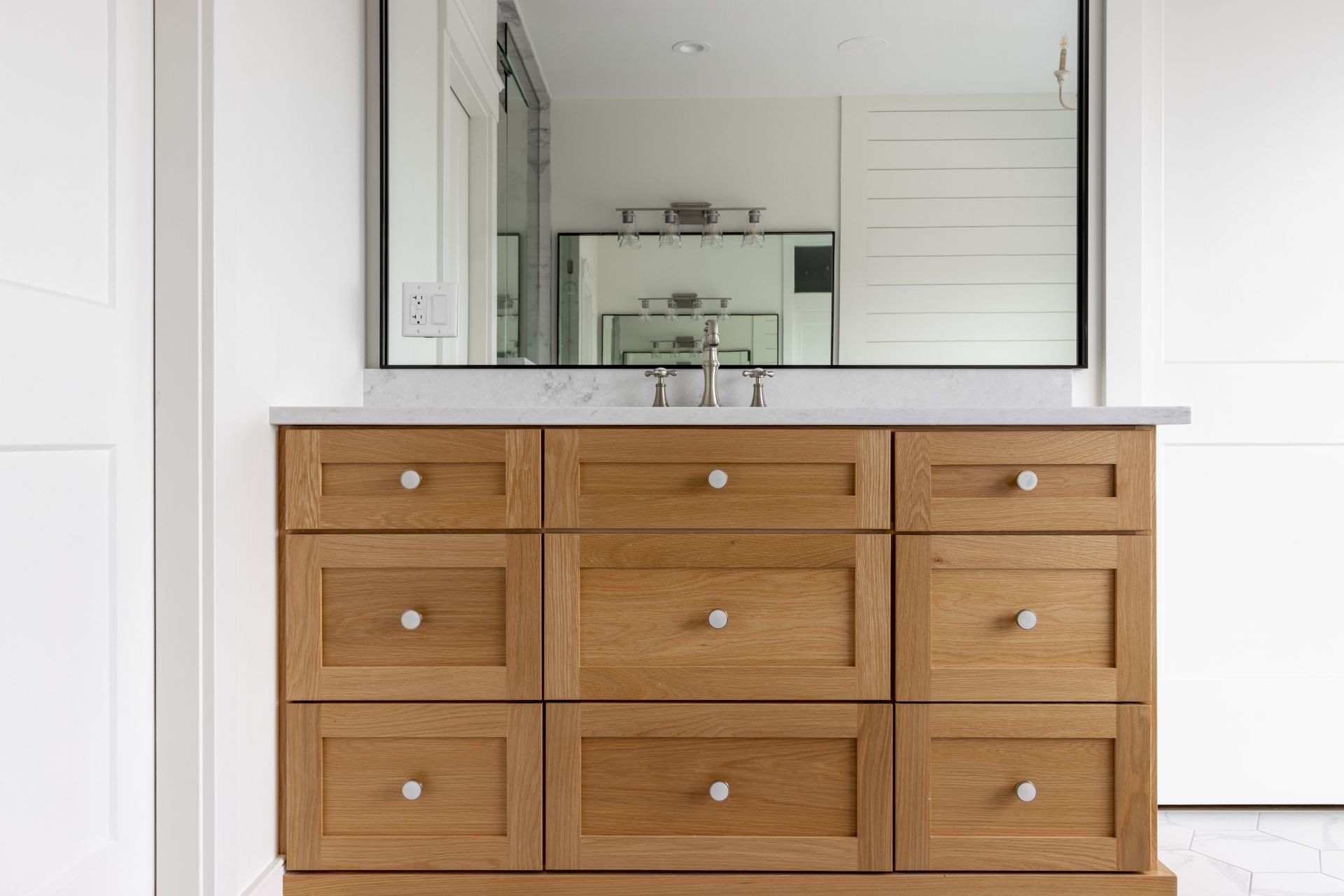 Wooden bathroom vanity with drawers and a large mirror.