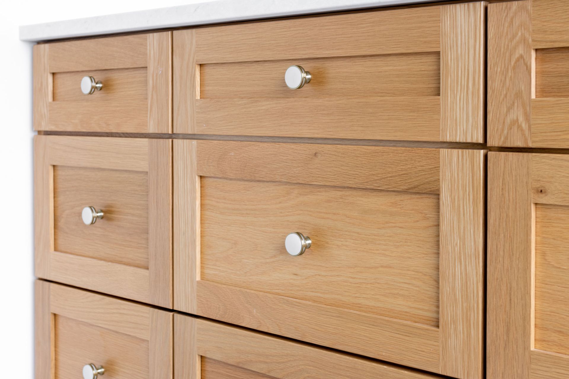 Wooden cabinet drawers with silver knobs; light wood grain.