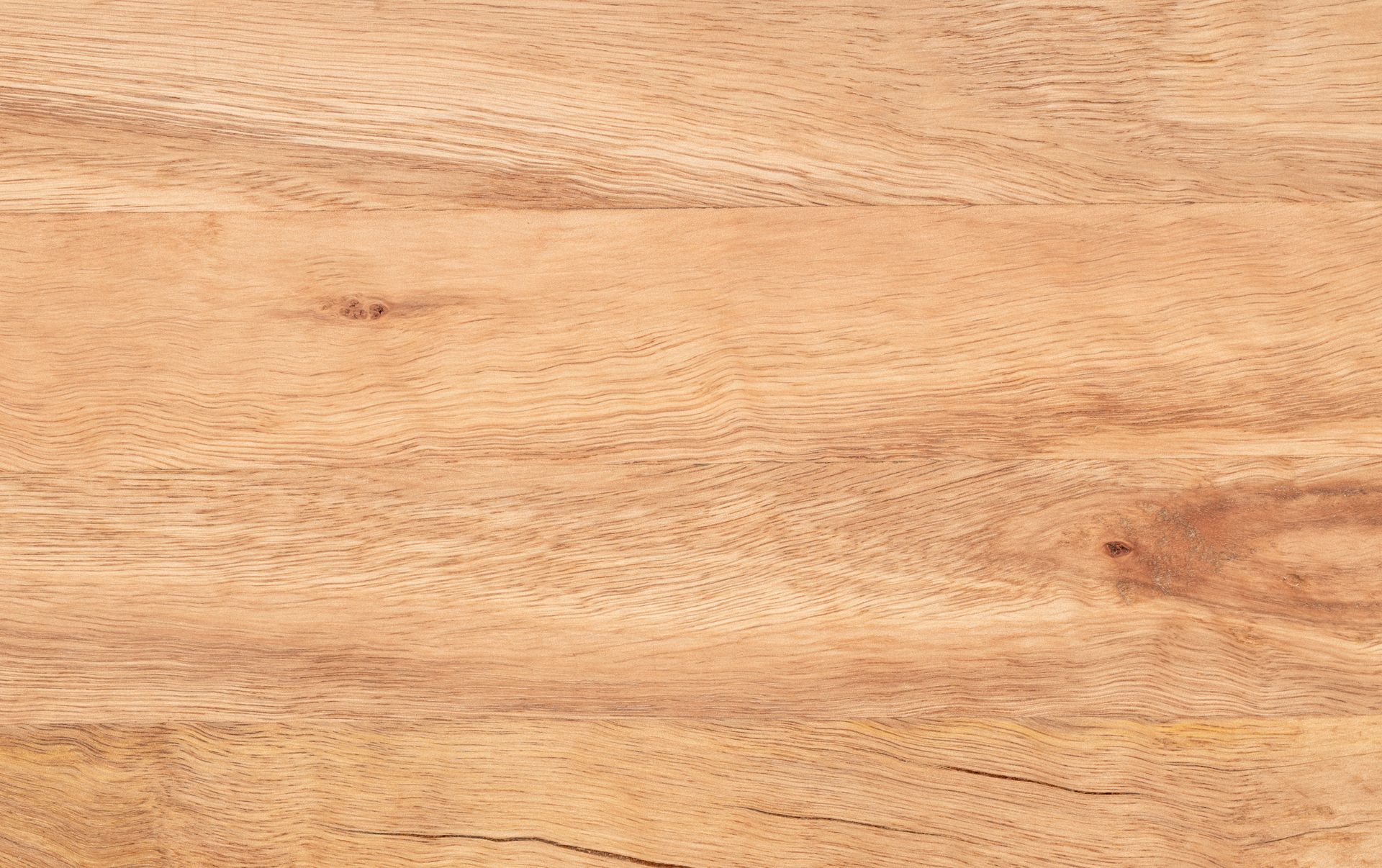 Close-up of a light brown wood grain surface, showing natural lines and textures.