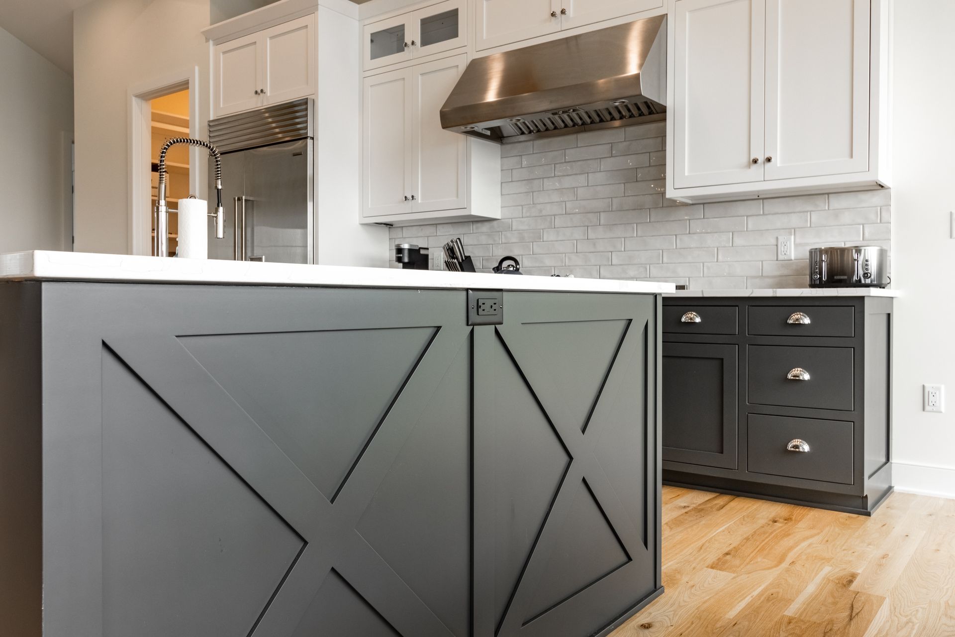 Gray and white kitchen with island, cabinets, and stainless steel range hood.