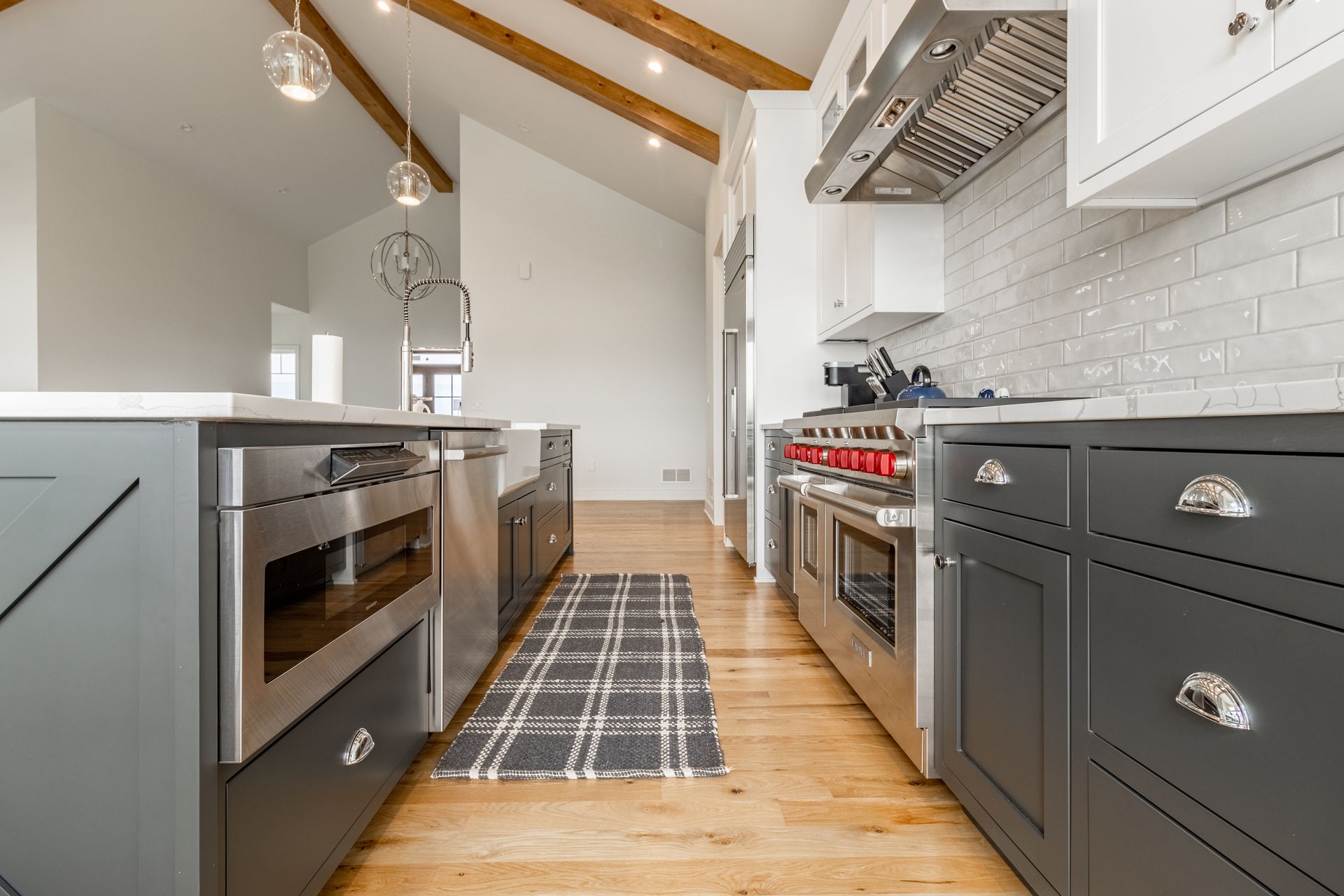Modern kitchen with gray and white cabinets, stainless steel appliances, and wood floors.