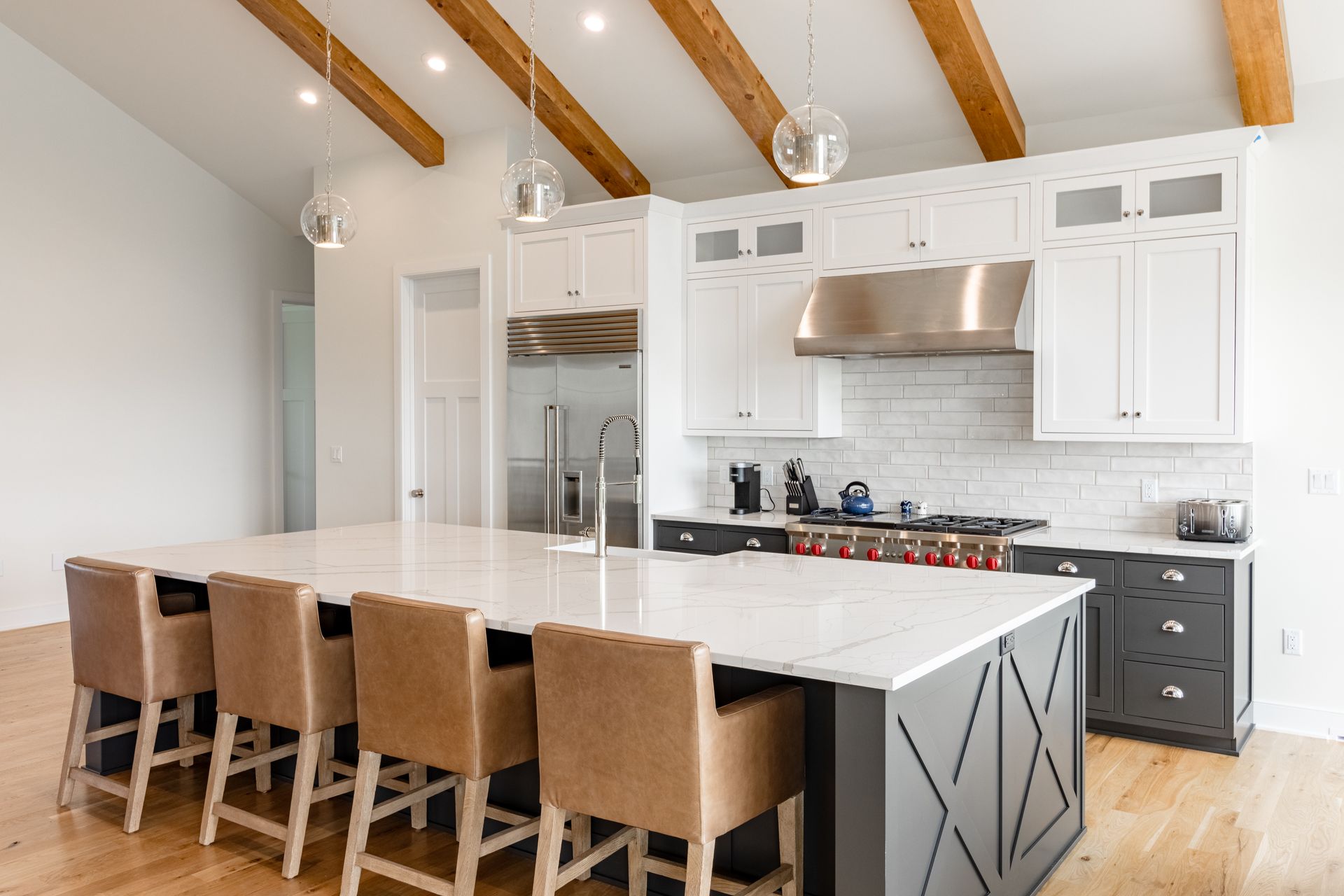Modern kitchen with a large island, white cabinets, and wooden beams.