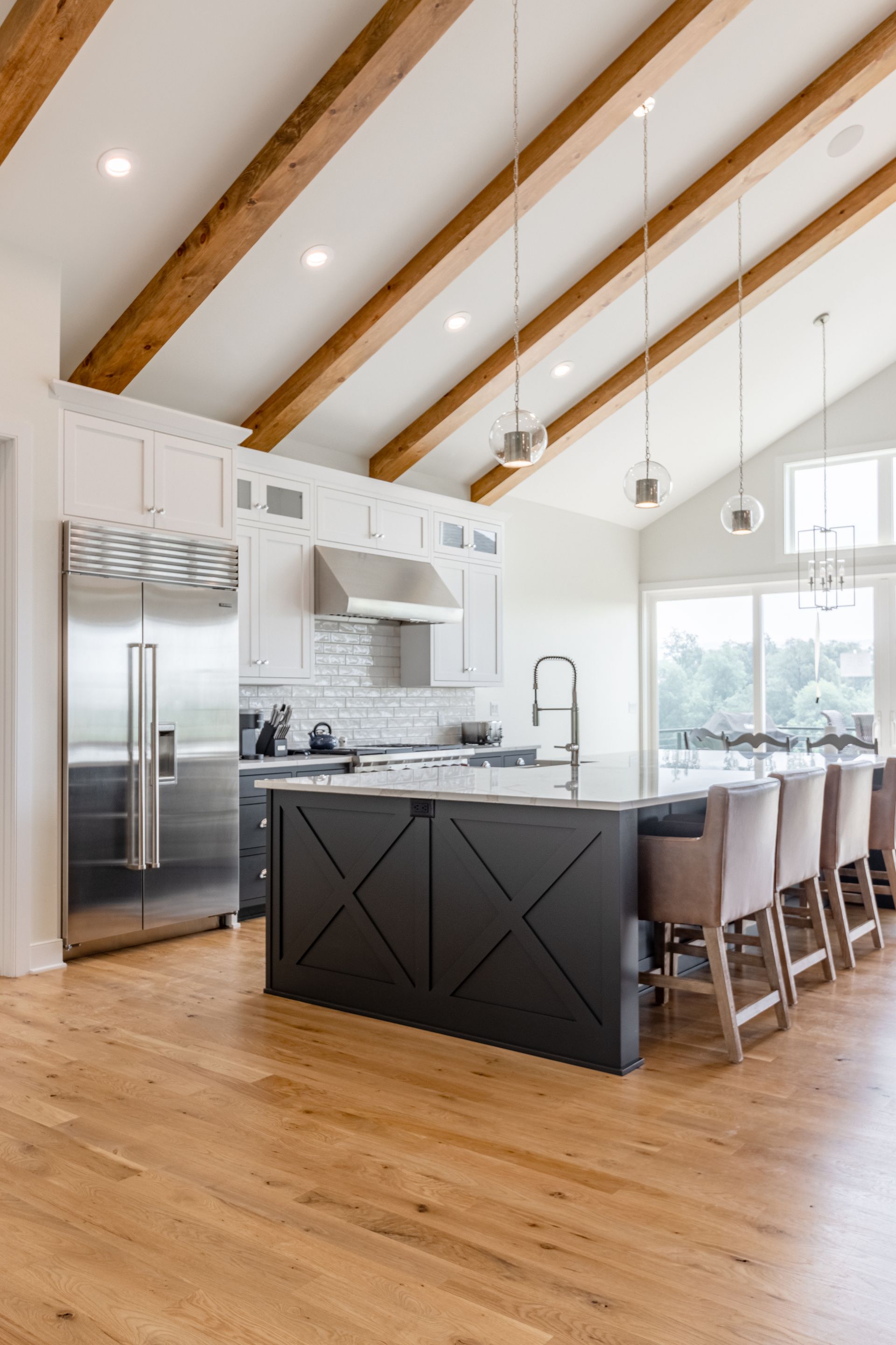 Spacious modern kitchen with vaulted ceiling, wood beams, and large island with seating.