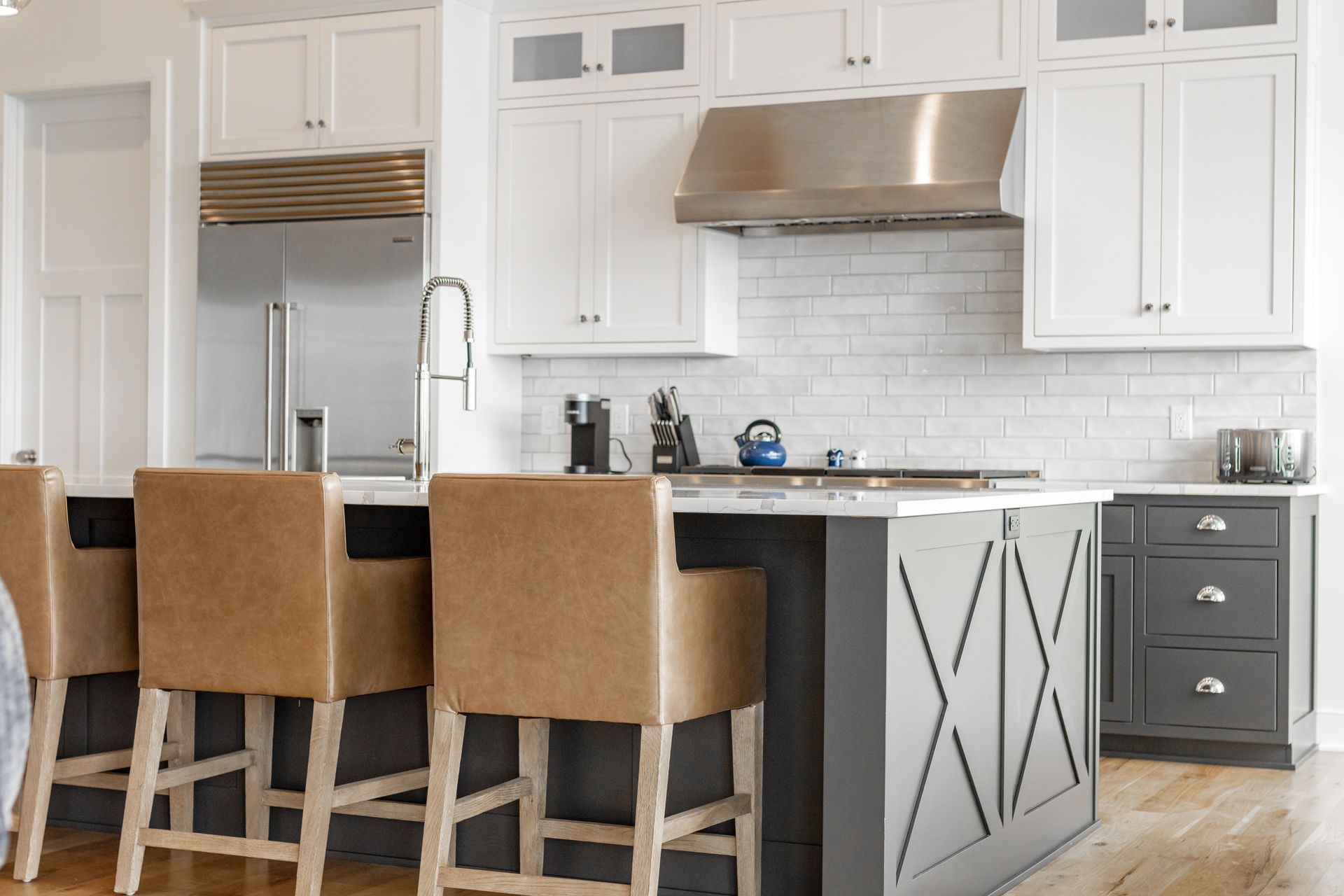 Modern kitchen with white cabinets, stainless steel appliances, and a gray island with bar stools.