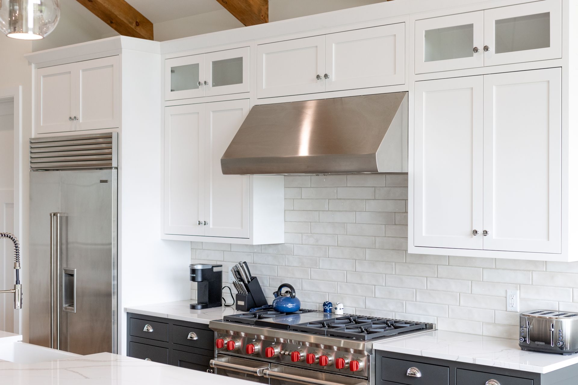 White kitchen with stainless steel appliances, stove, and cabinets.
