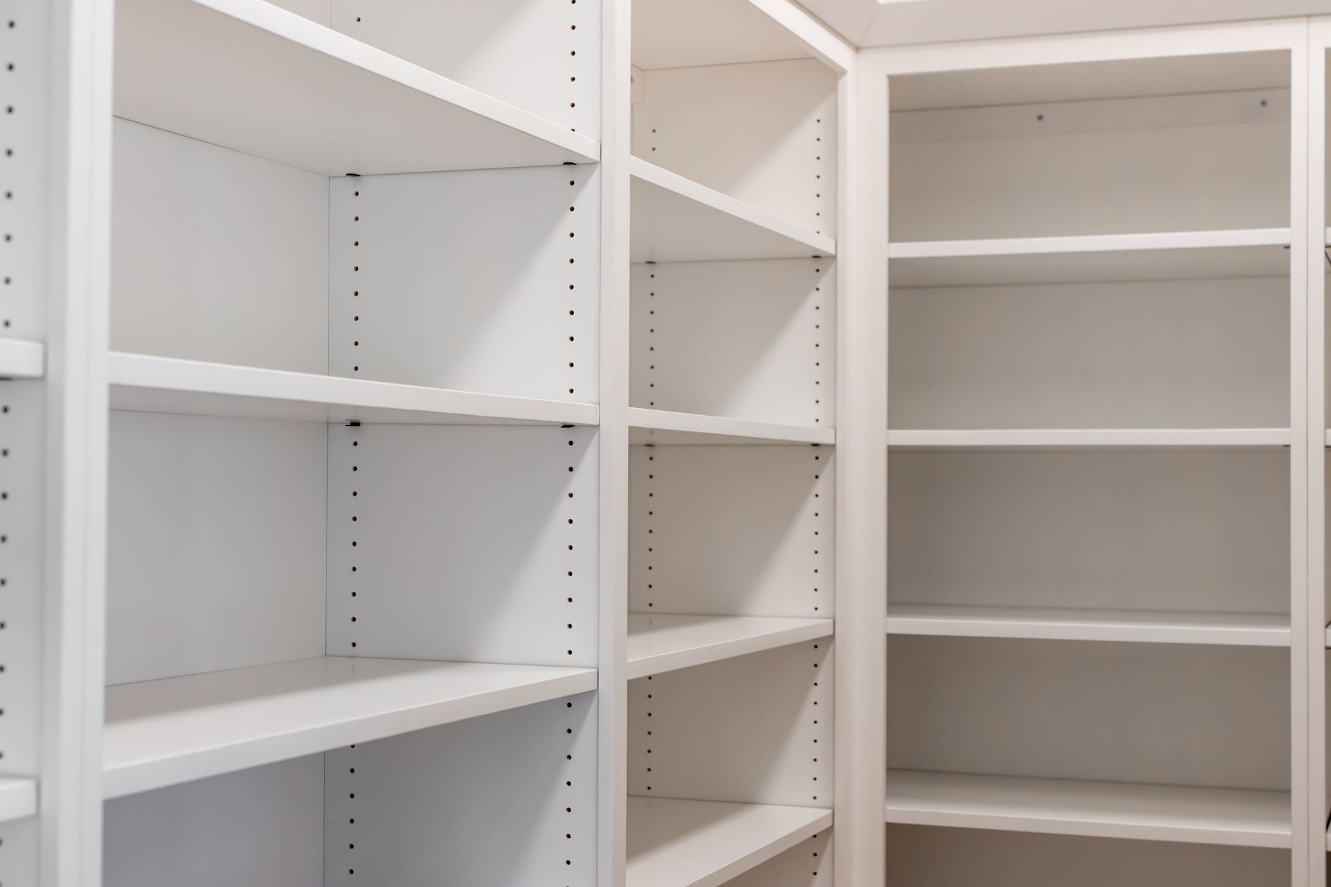 Empty white built-in bookshelves in a room, with adjustable shelf positions.