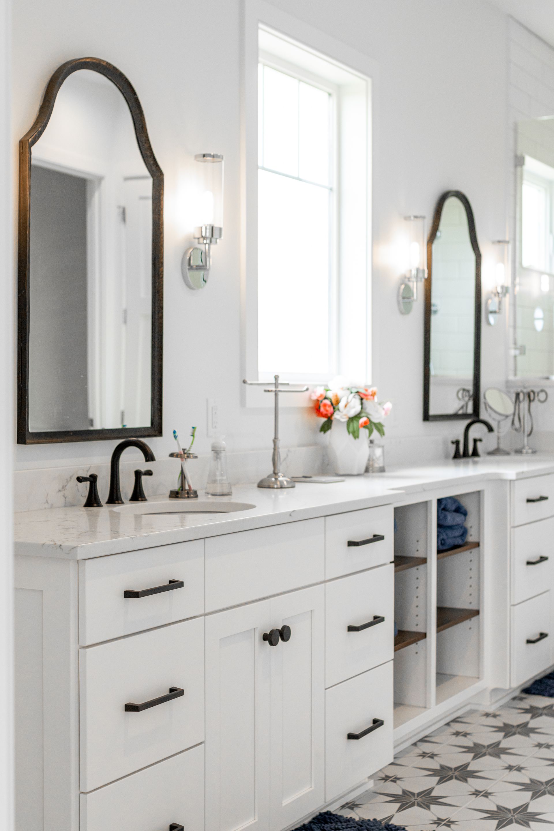 White bathroom with two vanities, black accents, and floral decor.