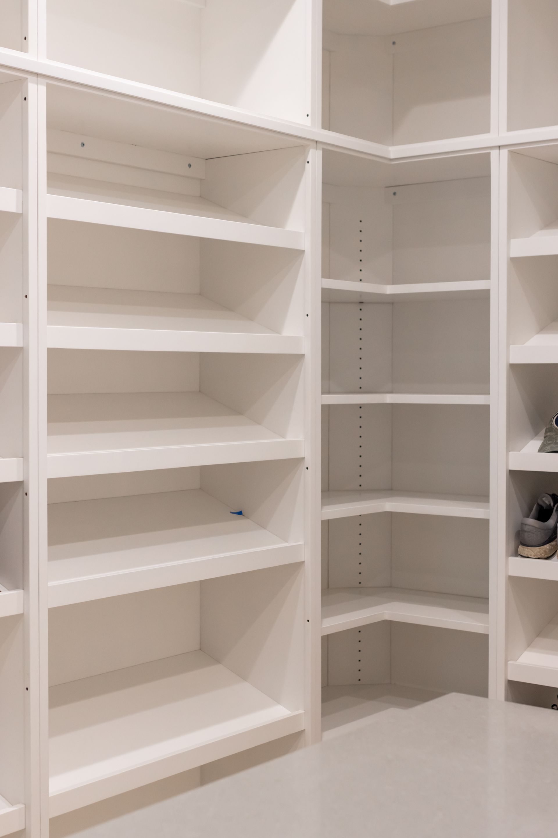 White, built-in shelving unit in a closet. Shelves form a corner and have varying heights.