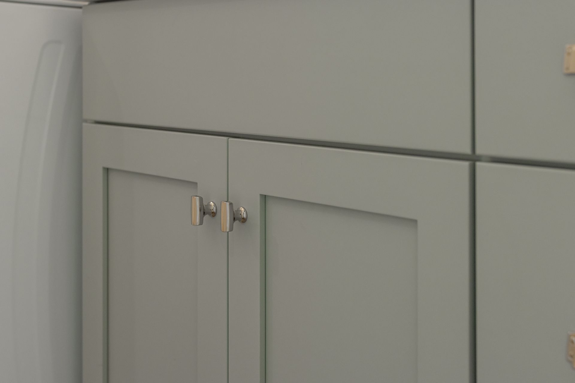 Gray kitchen cabinets with silver knobs.