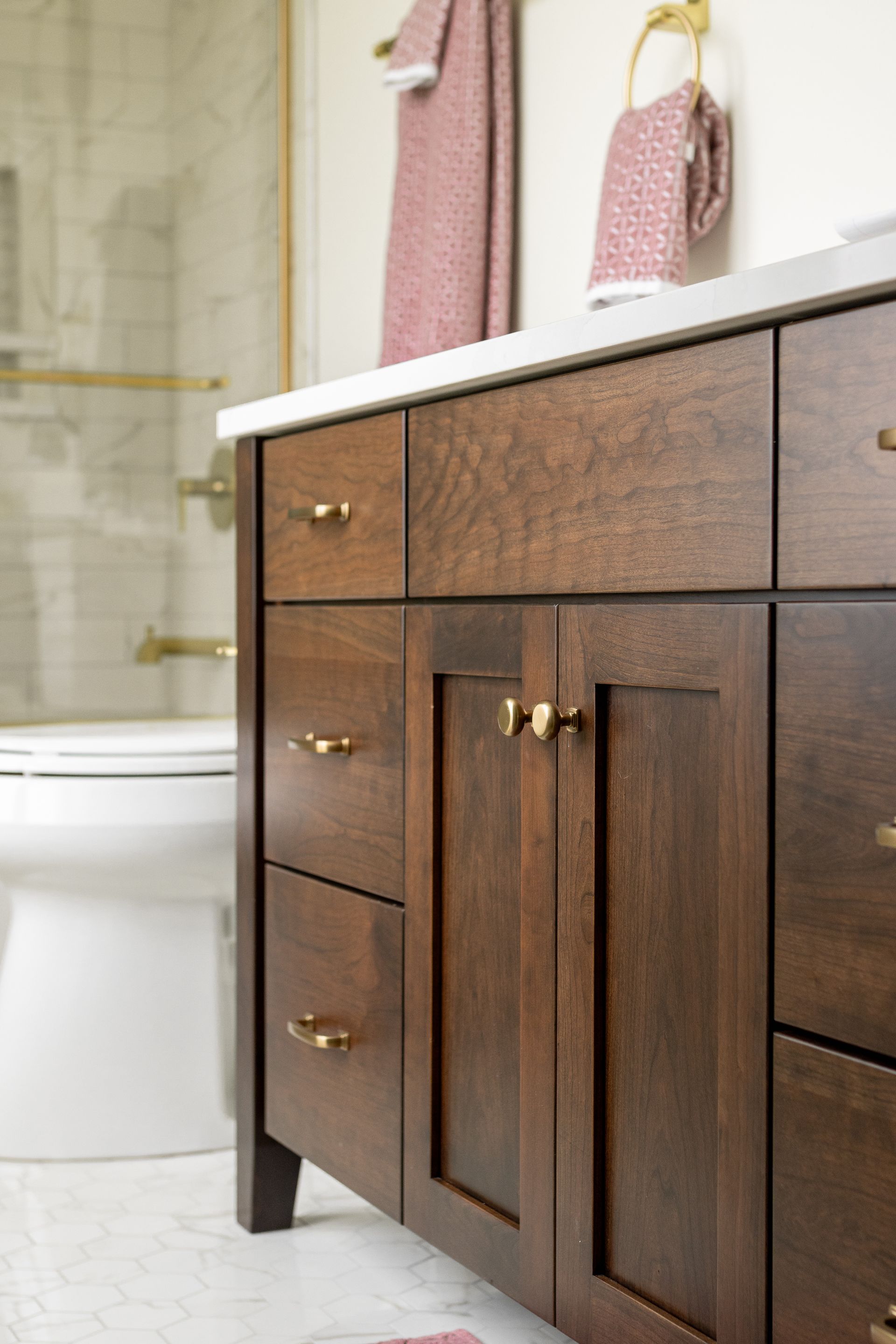 Bathroom vanity with dark wood cabinets, gold hardware, and a white countertop.