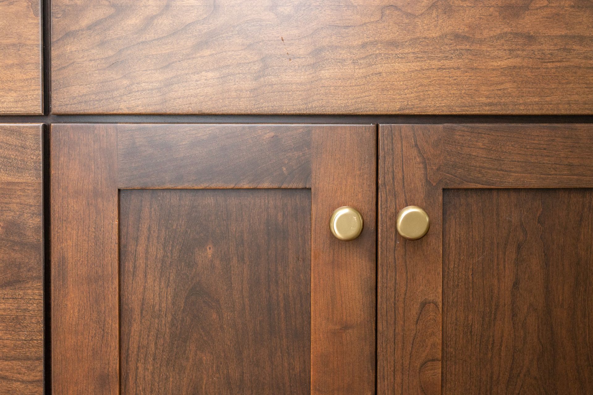 Wooden cabinet doors with gold knobs. Dark brown stain.