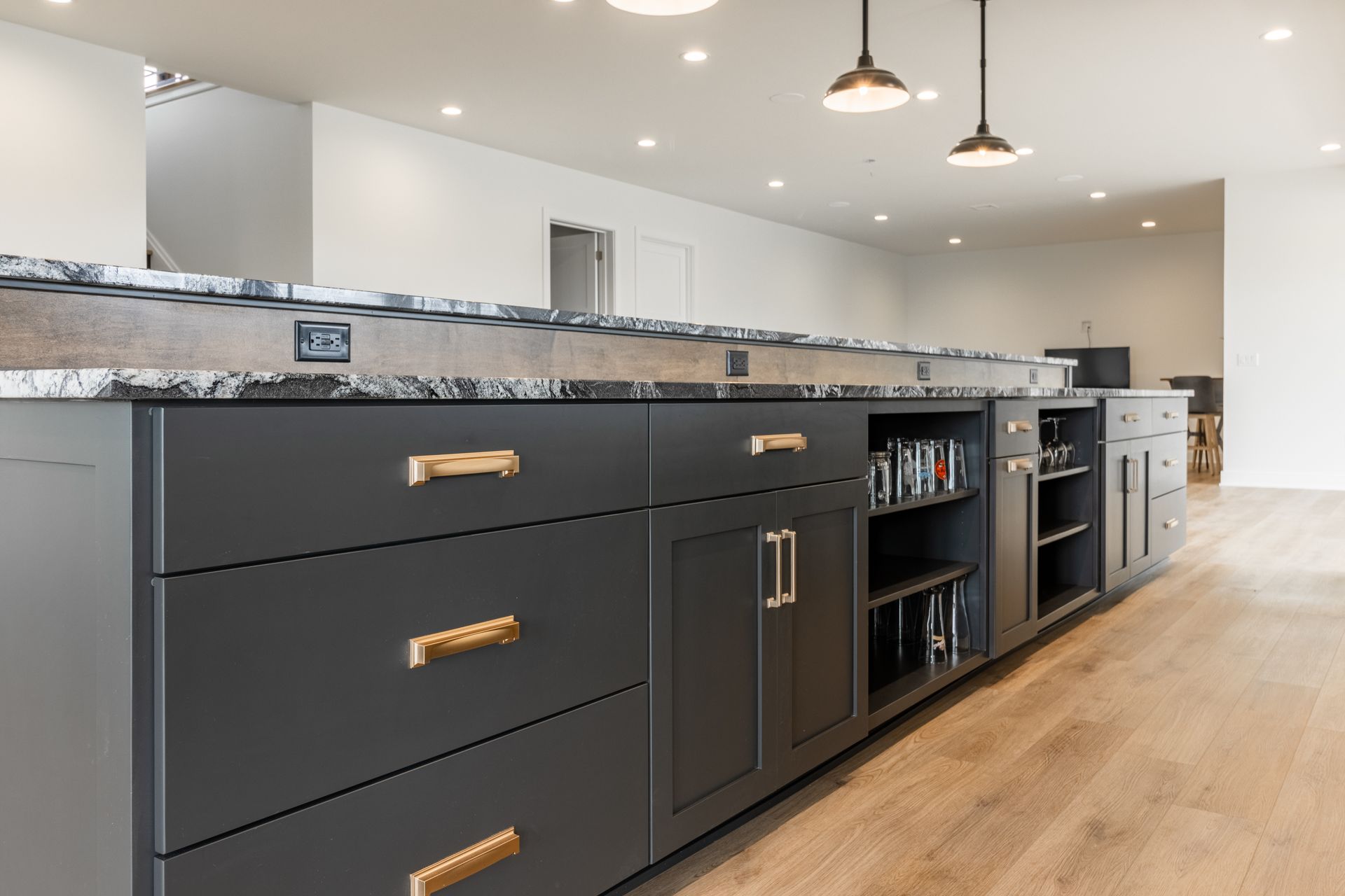 Dark gray kitchen island with granite countertop, gold hardware, and built-in storage.