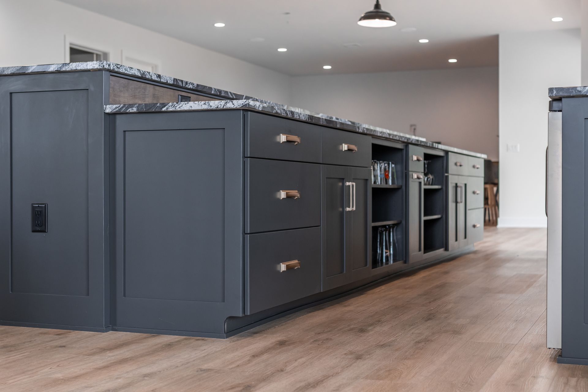 Dark gray kitchen island with drawers, cabinets, and a granite countertop.